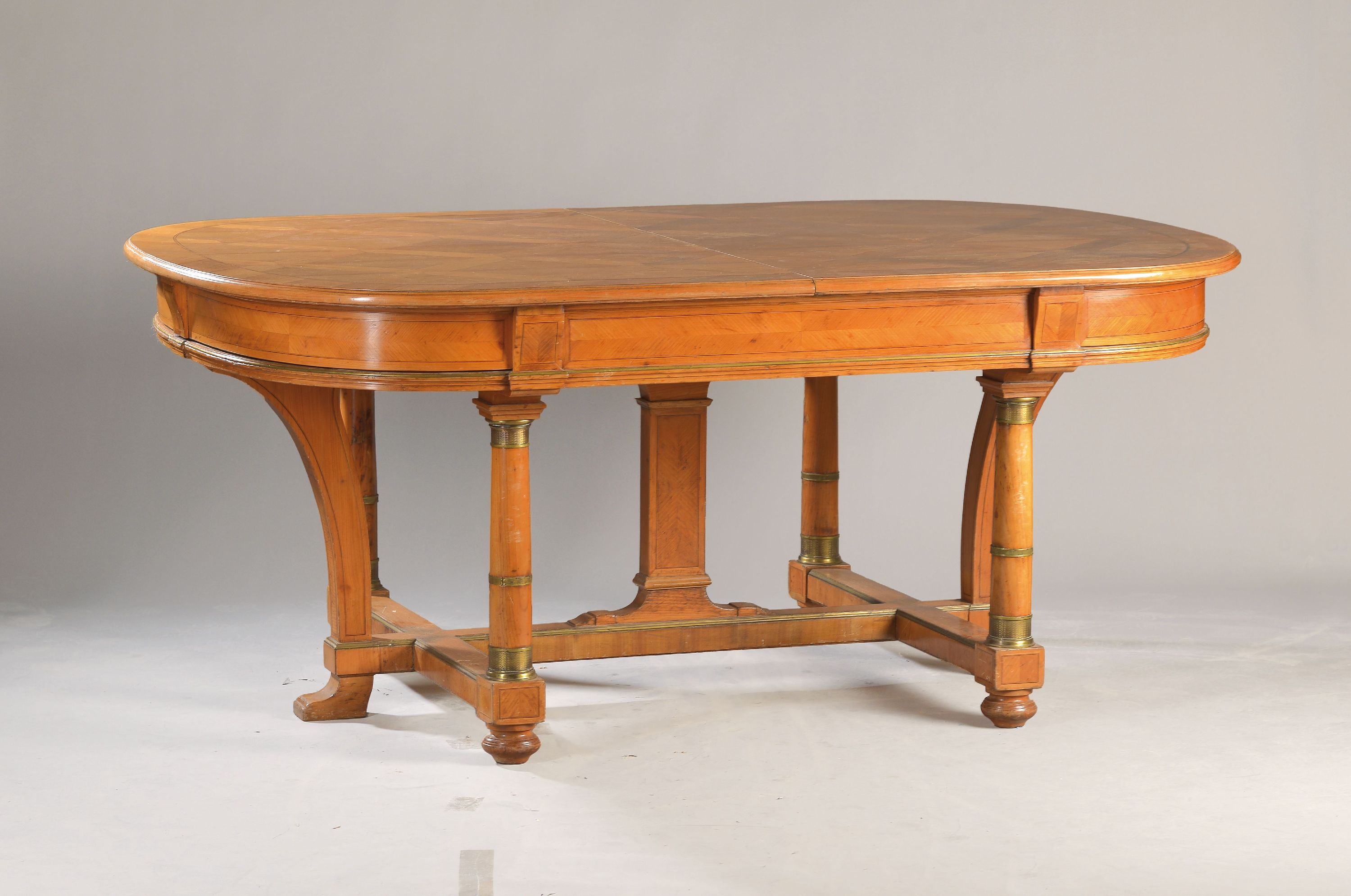 Großer Ausziehtisch, 19.Jh., Kirschbaumfurnier, z.T. massiv, Vollsäulendekor bei den Beinen, Messingapplikationen, Platte mit Rautenmarketerie und ...