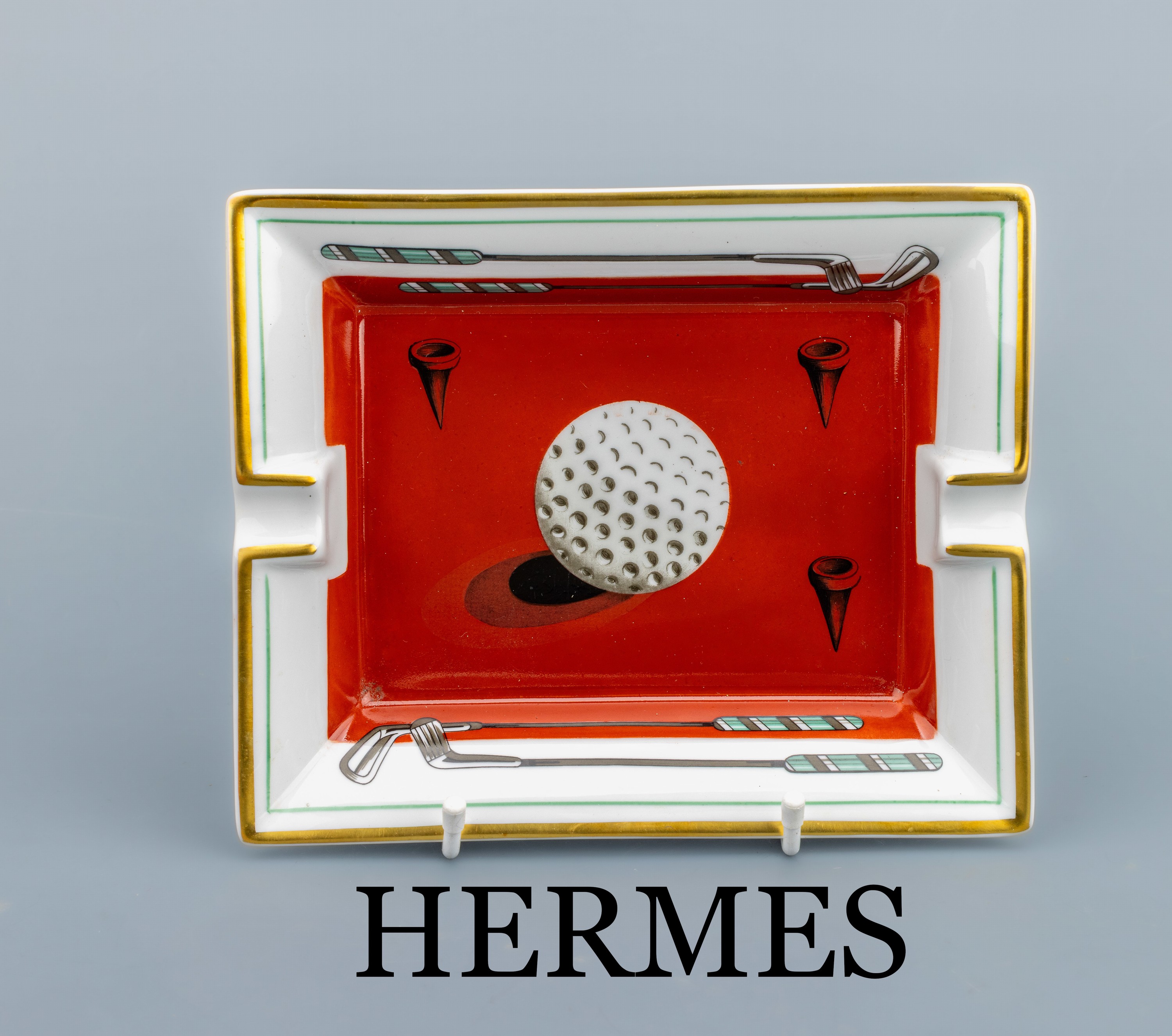 HERMES Aschenbecher, Porzellan korallen- roter Fond mit großem weißem Golfball und gold-Tees, Randseiten mit Golfschläger-MotivenRand ...
