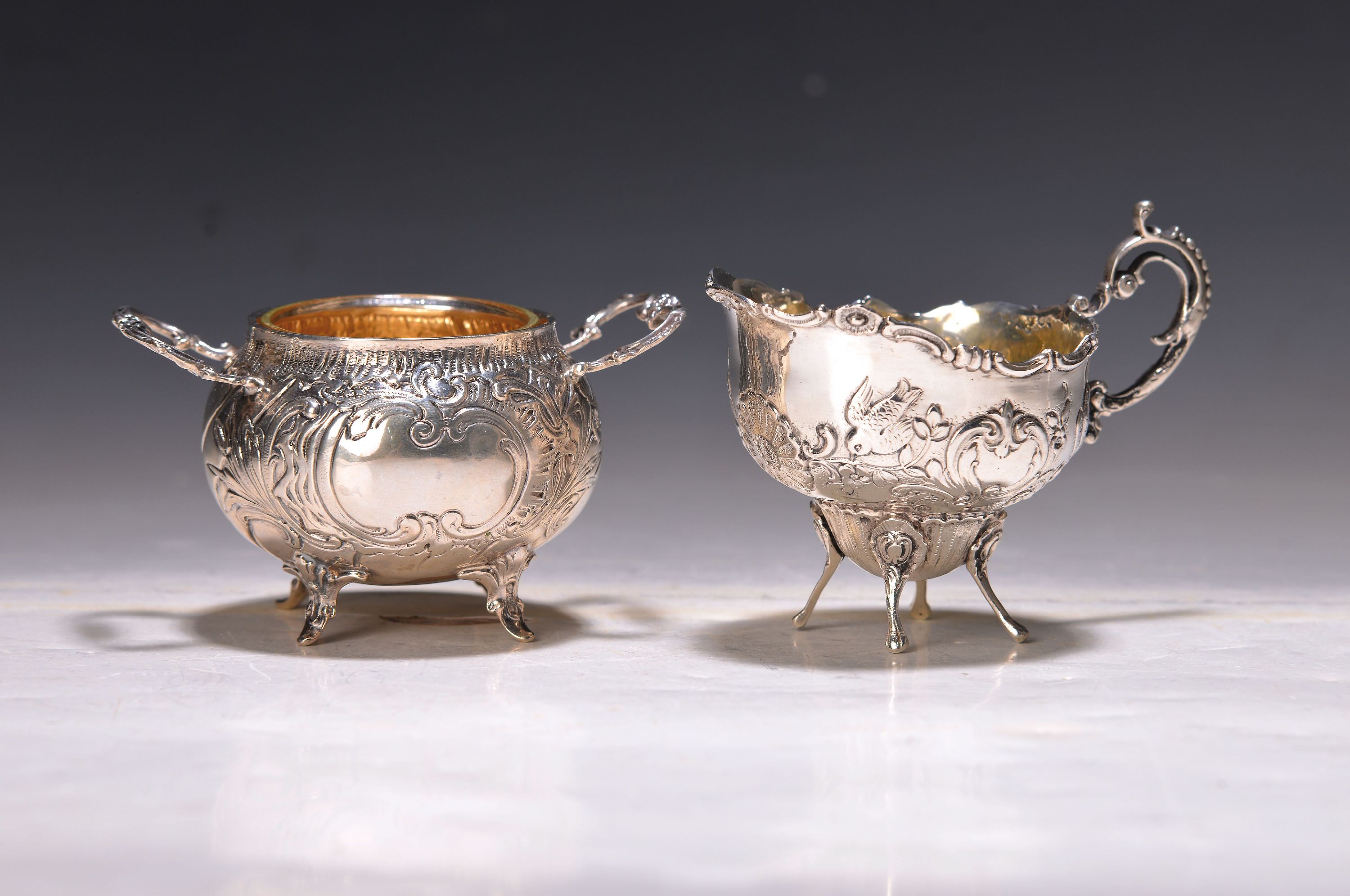 Milchkännchen und Zuckerschale, deutsch, 20. Jh., Rokokostil, 800er Silber, innen vergoldet, Rocaillendekor und Blumen, H. ca. 6-7 cm, ca. 165 g