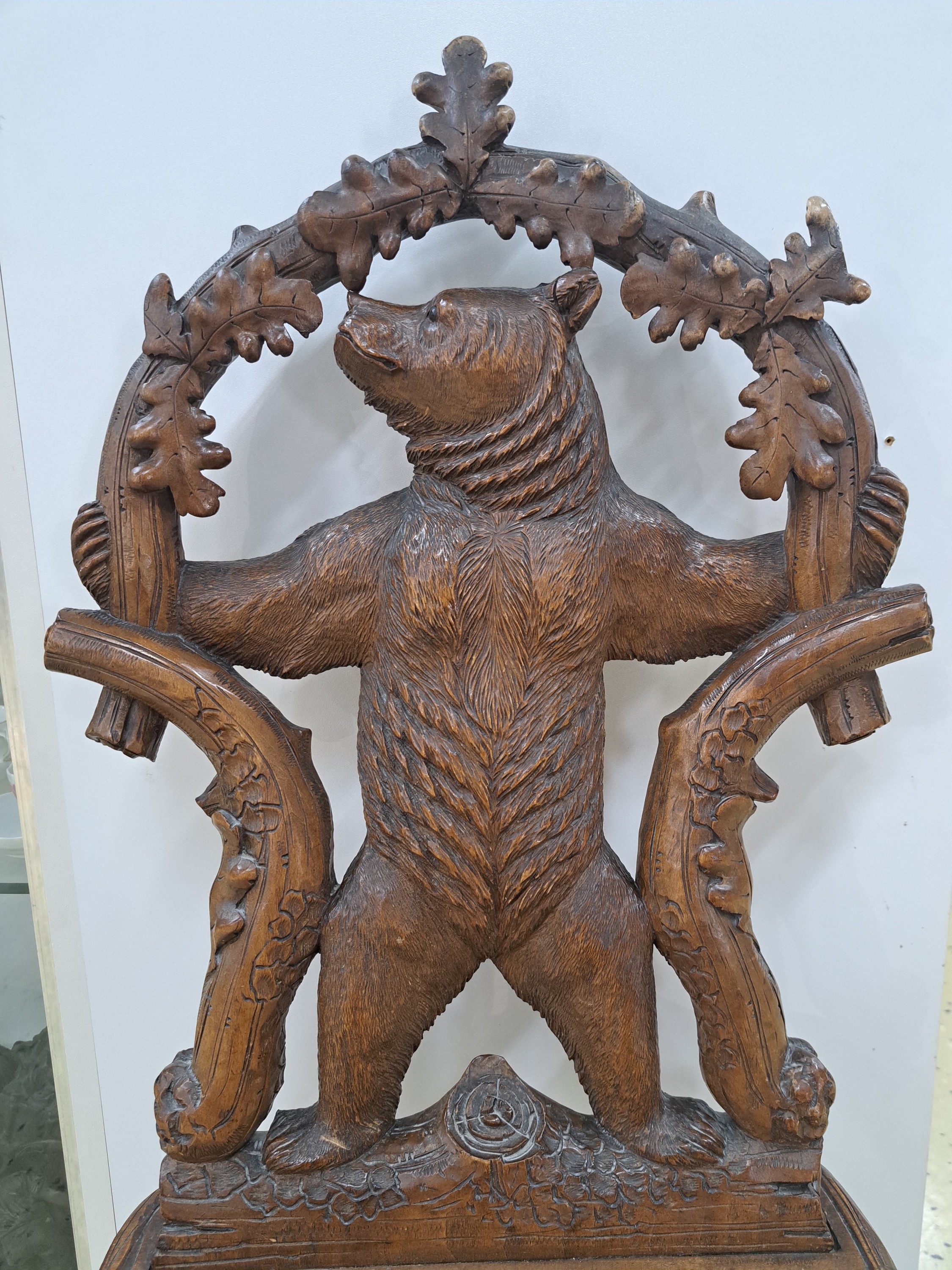Detail a: sog. Bärenstuhl, wohl Brienz, Schweiz, um 1880/90, Holz geschnitzt, Rücklehne mit stehendem Bären von Eichenstämmen mit Blättern eingerahmt, ...