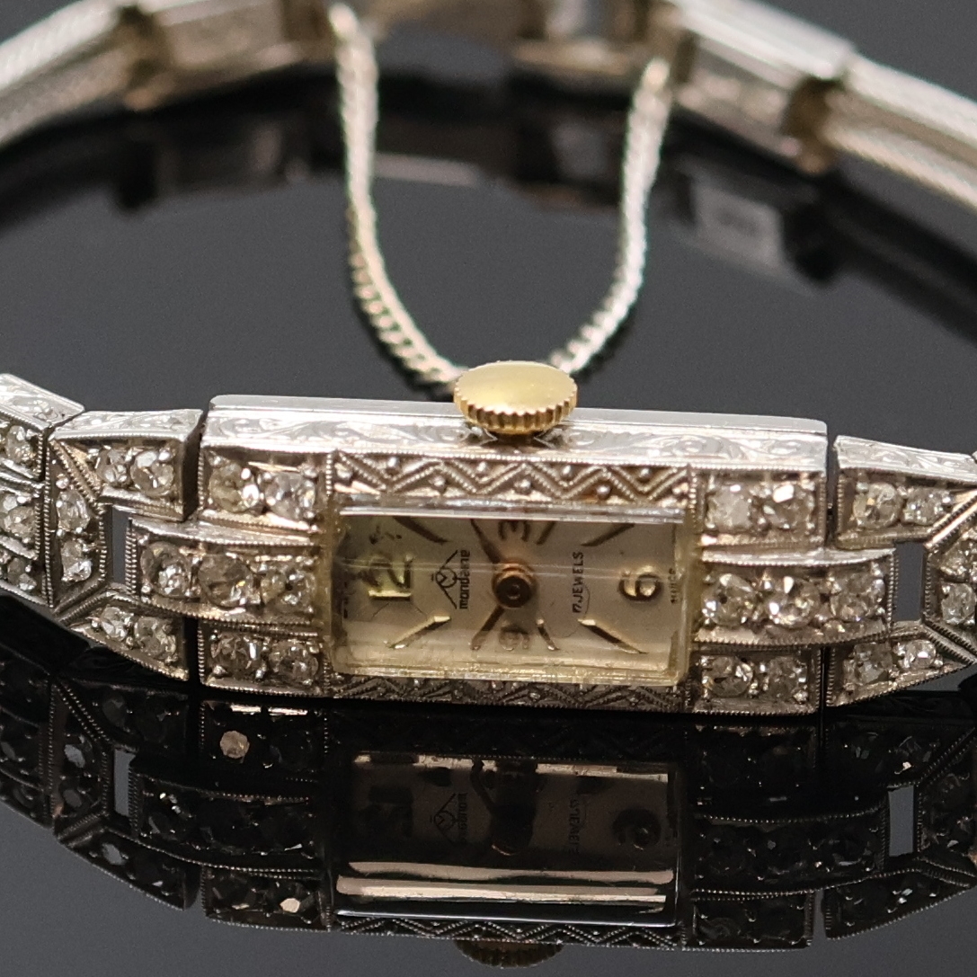 Detail a: Art-Deco Damenarmbanduhr in Platin mit Diamanten, Schweiz um 1920, Handaufzug, Geh. grav., Scharnierboden, Lünette sowie Bandanstöße aufw. m. ...