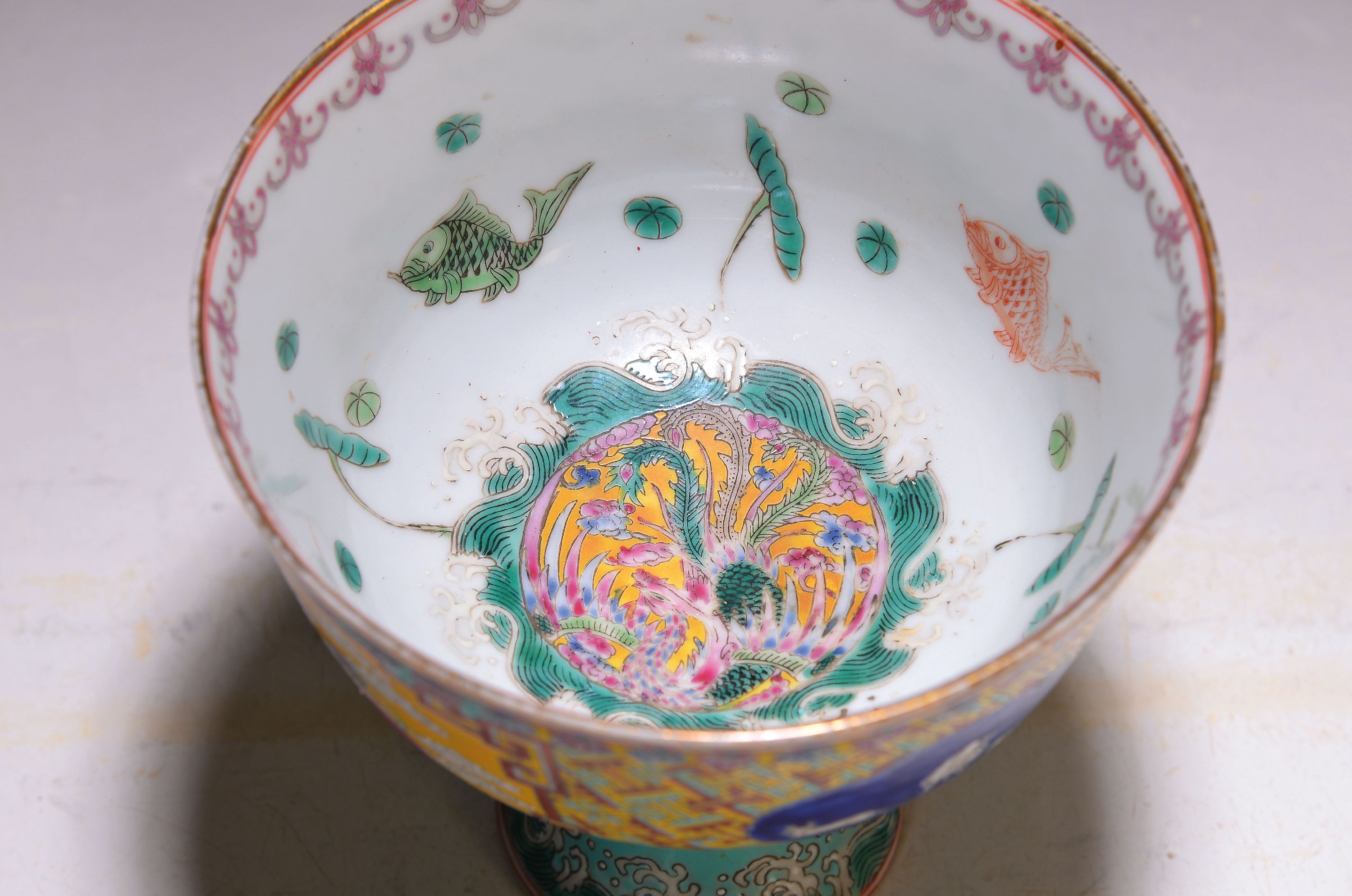 Detail a: Fußschale, China, um 1900, bunt bemalt, geom. Muster, in Feldern: Löwe, geflügelter Hirsch und Ziegen, innen mit Fischen bemalt, Goldrand, ...