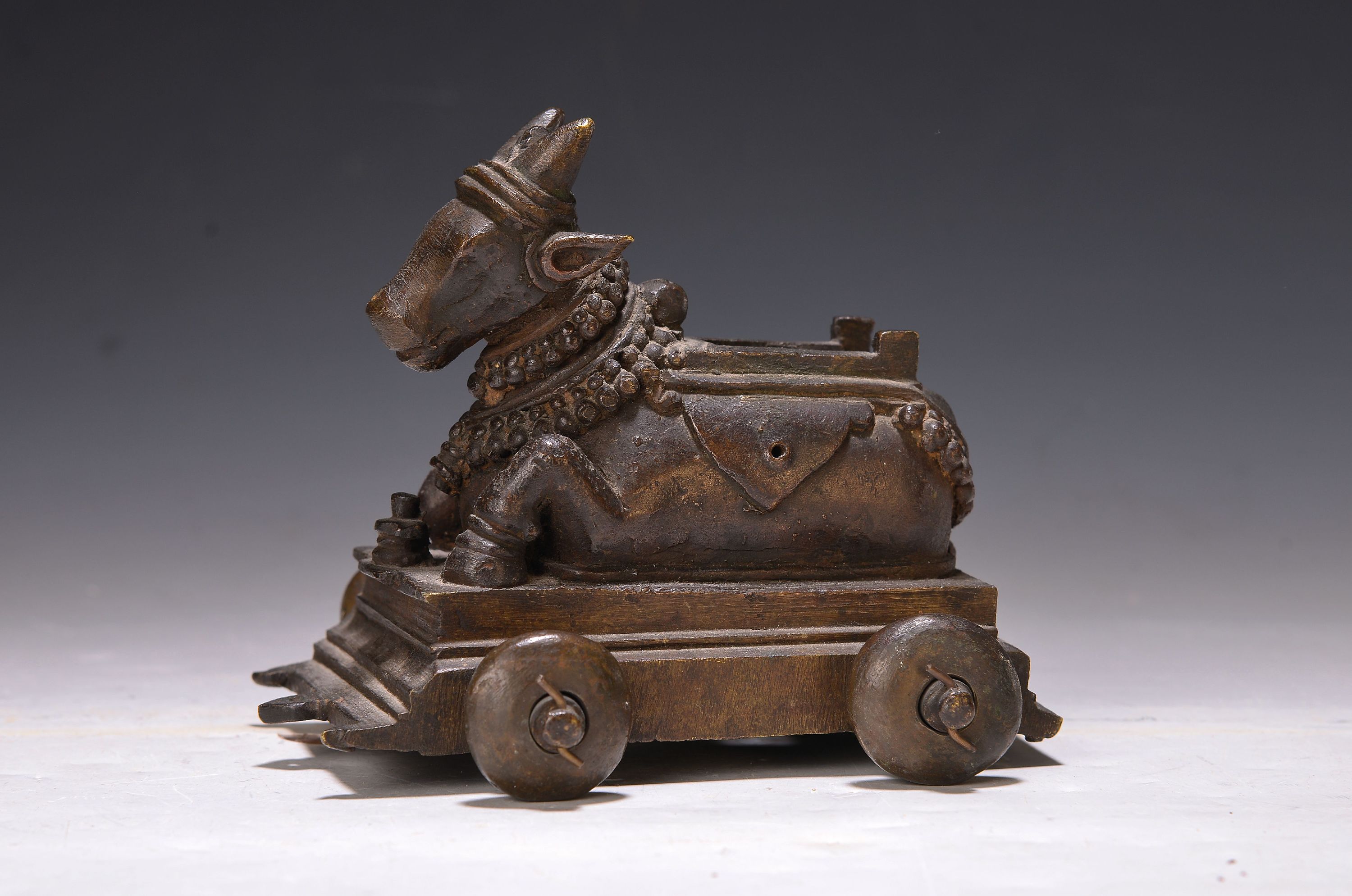 Detail a: Buddhamaske und vier Bronzestücke, Indien, 18.-19. Jh., Heilige Kuh Kamadhenu auf Rollen, oben mit Bohrung, zwei versch. Öllampen, Messingschüssel ...