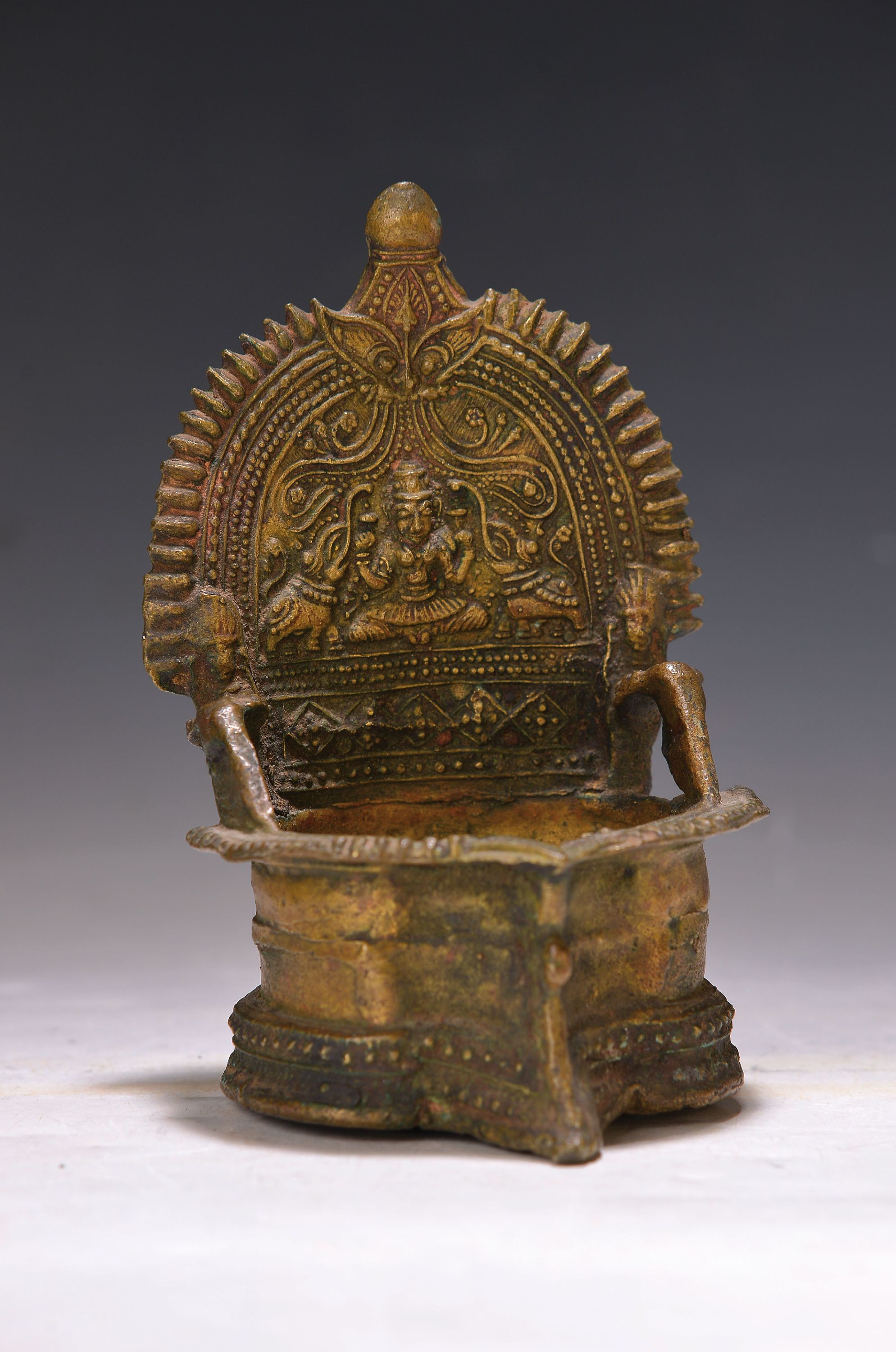 Detail d: Buddhamaske und vier Bronzestücke, Indien, 18.-19. Jh., Heilige Kuh Kamadhenu auf Rollen, oben mit Bohrung, zwei versch. Öllampen, Messingschüssel ...