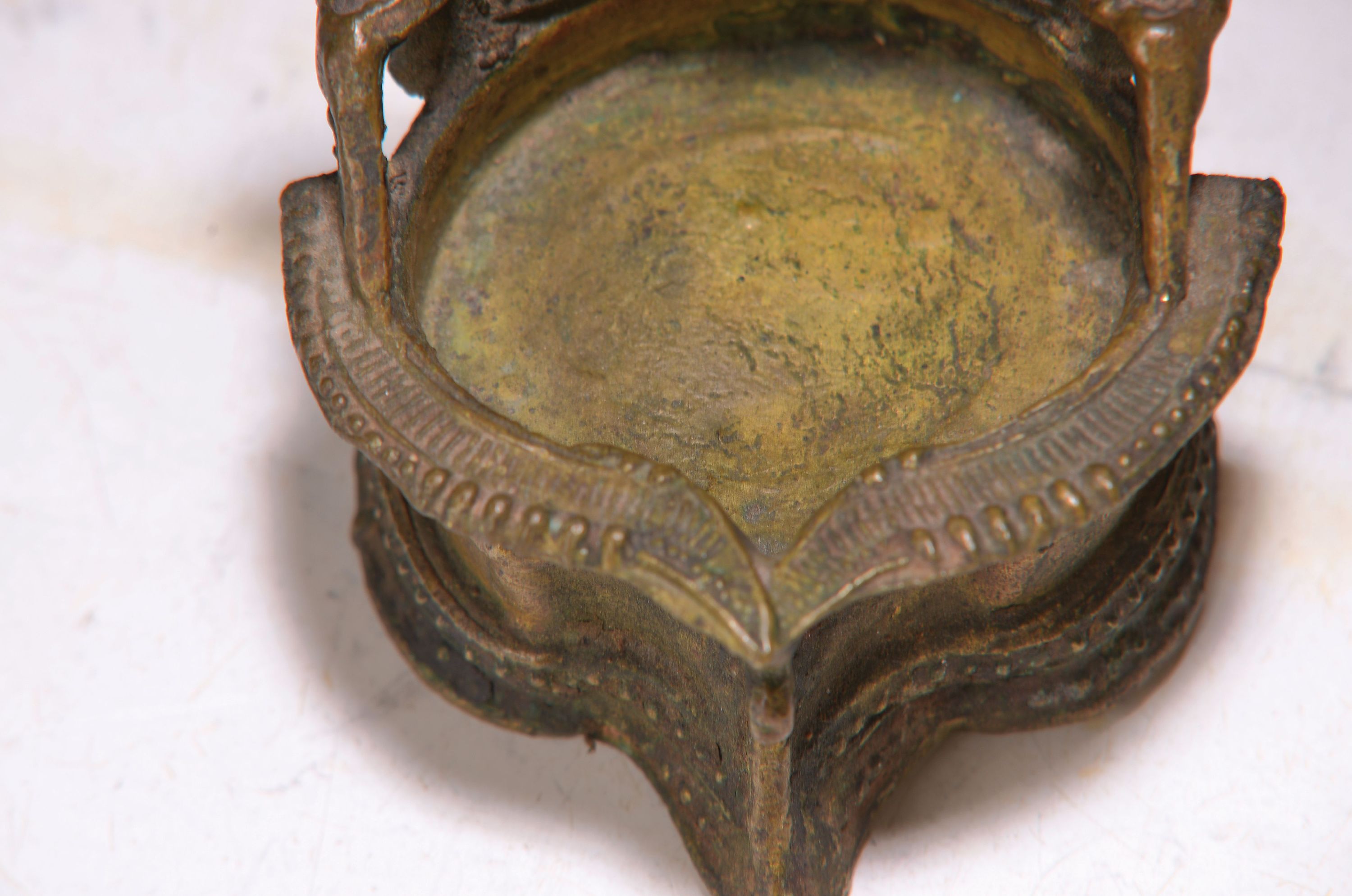 Detail f: Buddhamaske und vier Bronzestücke, Indien, 18.-19. Jh., Heilige Kuh Kamadhenu auf Rollen, oben mit Bohrung, zwei versch. Öllampen, Messingschüssel ...