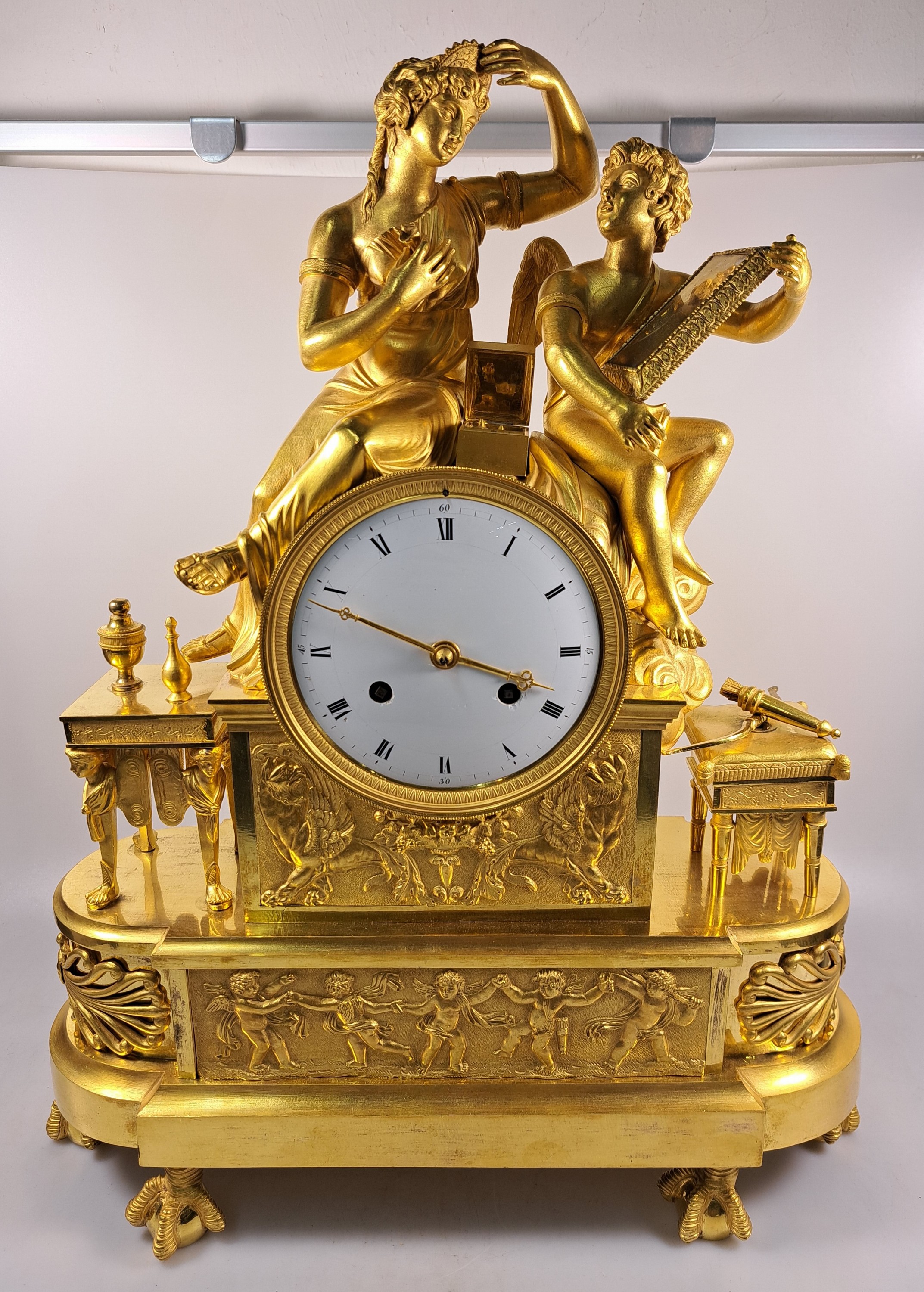 Detail a: Pendule, Frankreich, um 1810-20, Bronze matt- und glanzvergoldet, im Sockel tanzende Putti, neben Uhr Tabouret darauf Pfeilköcher mit Bogen, ...