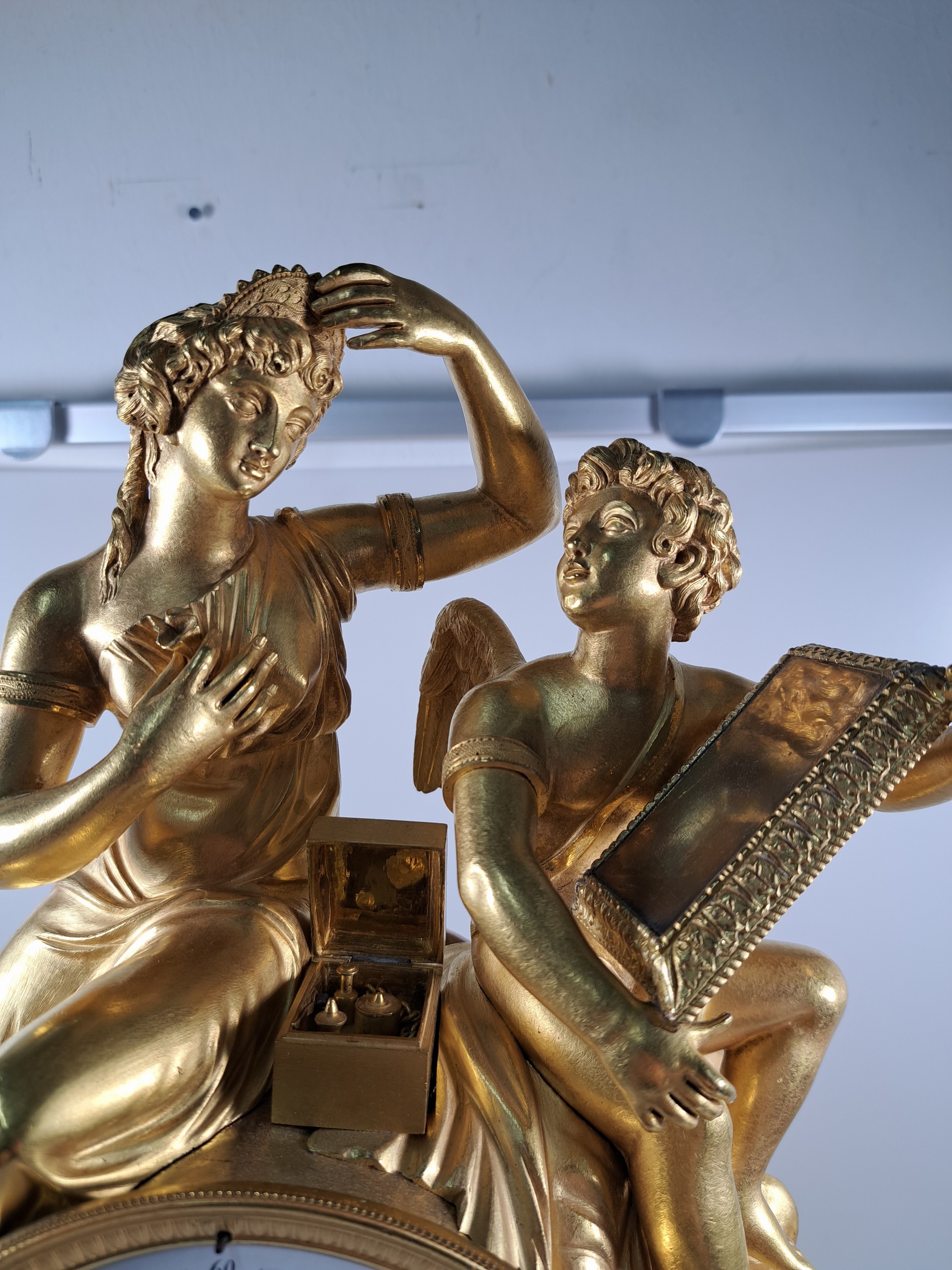 Detail b: Pendule, Frankreich, um 1810-20, Bronze matt- und glanzvergoldet, im Sockel tanzende Putti, neben Uhr Tabouret darauf Pfeilköcher mit Bogen, ...