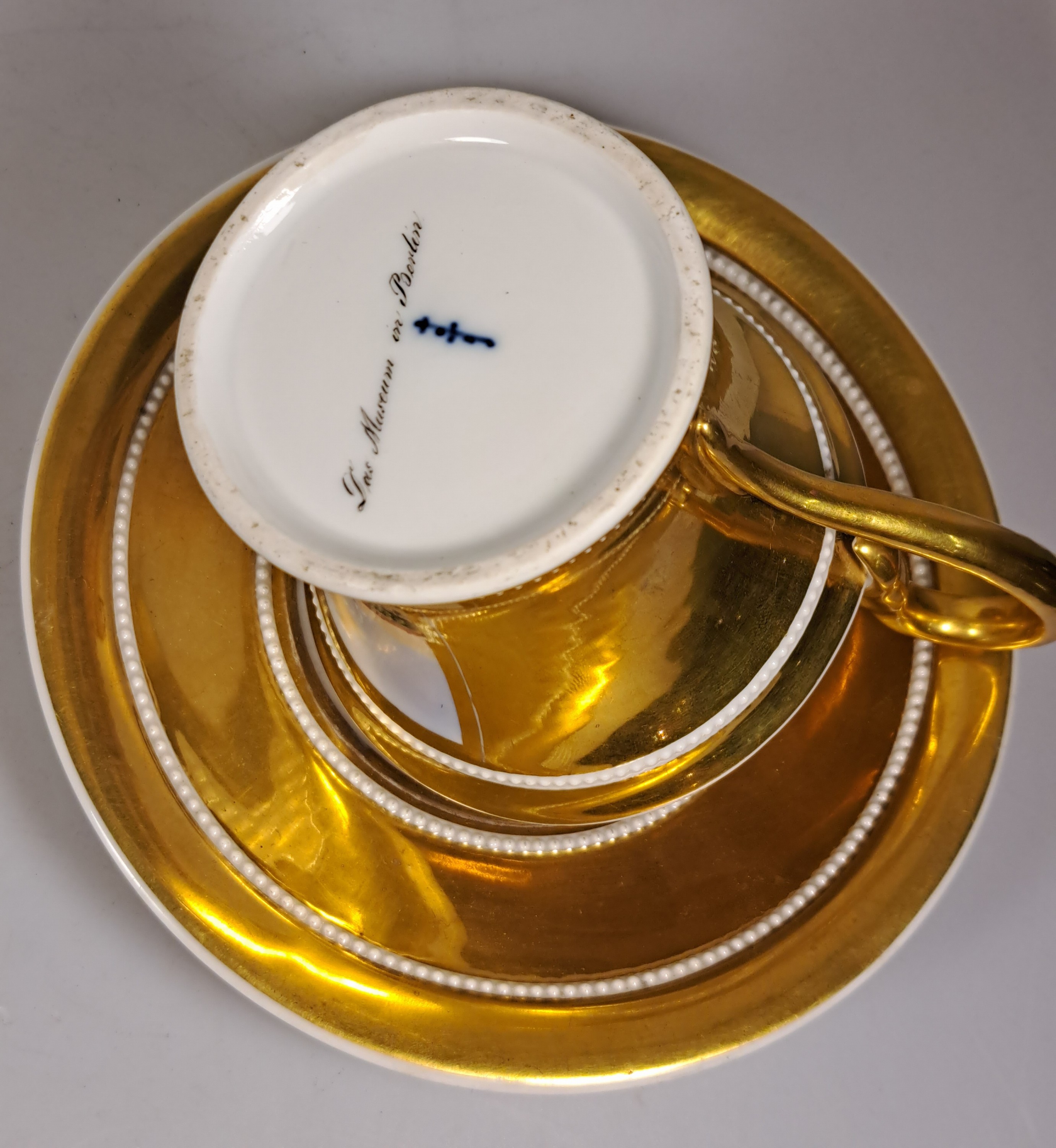 Detail l: Tasse mit Untertasse, KPM Berlin, um 1820, Porzellan, reich glanzvergoldet, in Kartusche feine bunte Malerei des Museums in Berlin mit ...
