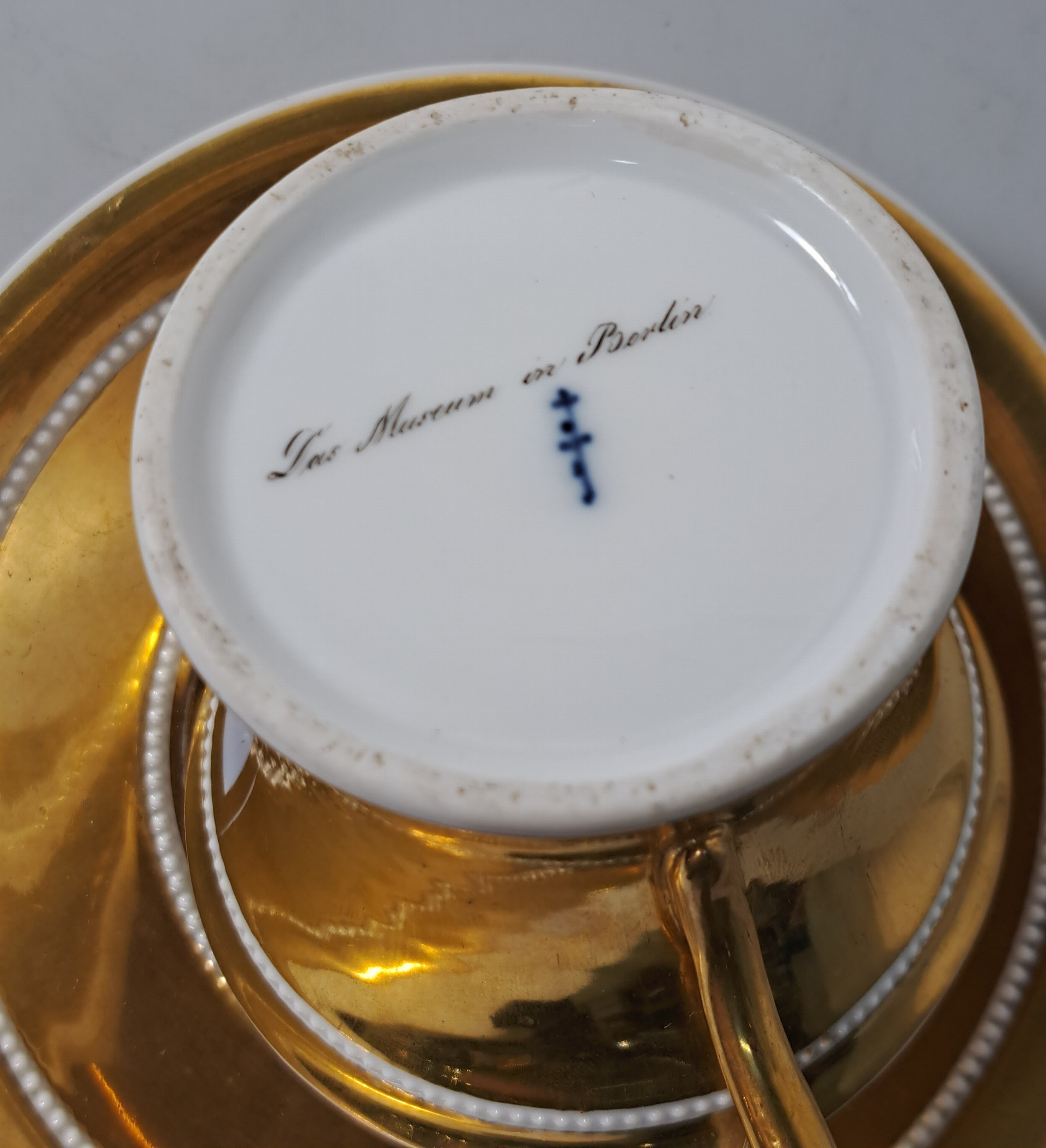 Detail m: Tasse mit Untertasse, KPM Berlin, um 1820, Porzellan, reich glanzvergoldet, in Kartusche feine bunte Malerei des Museums in Berlin mit ...