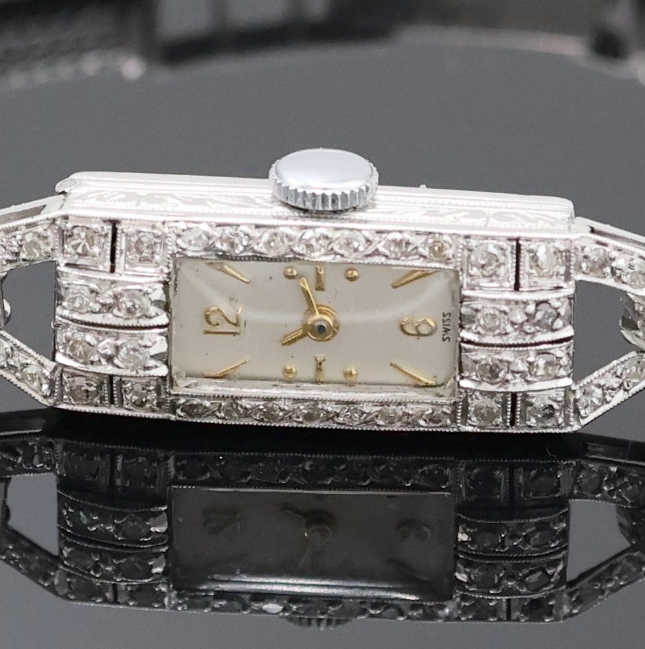 Detail a: Art Deco Damenarmbanduhr in Platin mit Diamanten, Schweiz um 1920, Handaufzug, Scharnierboden dell., Band in WG 750/000, Geh. sowie Bandanstöße mit ...
