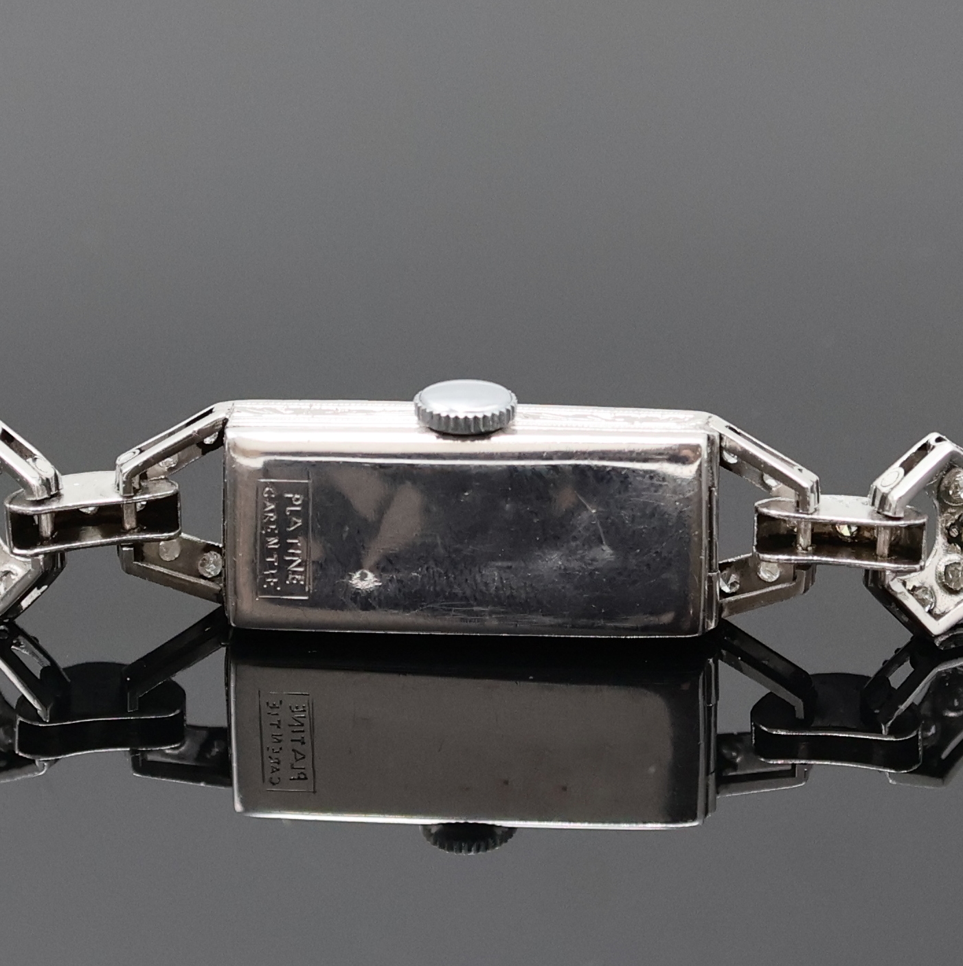 Detail d: Art Deco Damenarmbanduhr in Platin mit Diamanten, Schweiz um 1920, Handaufzug, Scharnierboden dell., Band in WG 750/000, Geh. sowie Bandanstöße mit ...