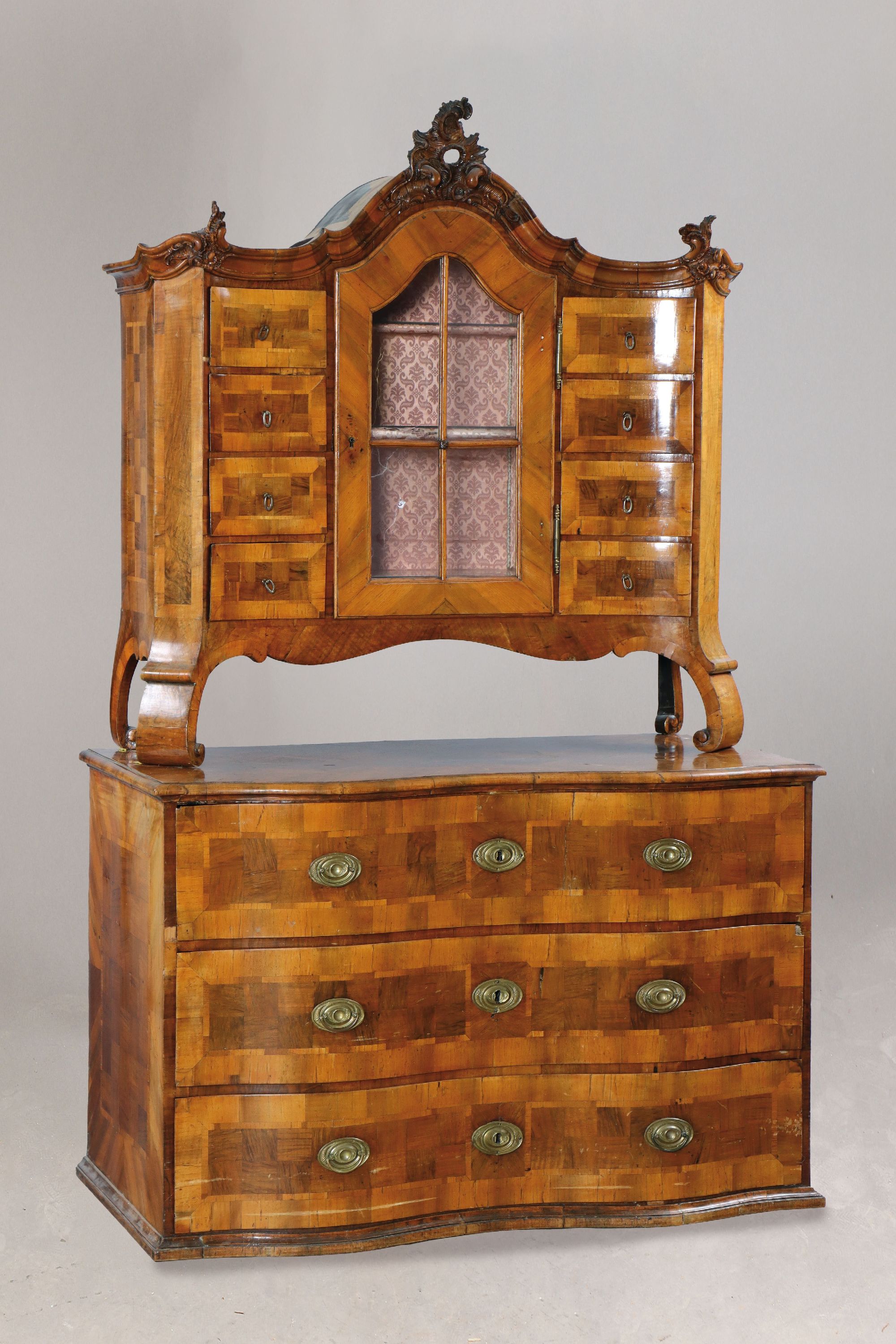 Aufsatzkommode, Barock, um 1760, Nußbaumfurnier, Aufsatz eintürig verglast und versprosst, 8 Schubladen, Kommodenunterteil doppelt geschweift mit 3 ...