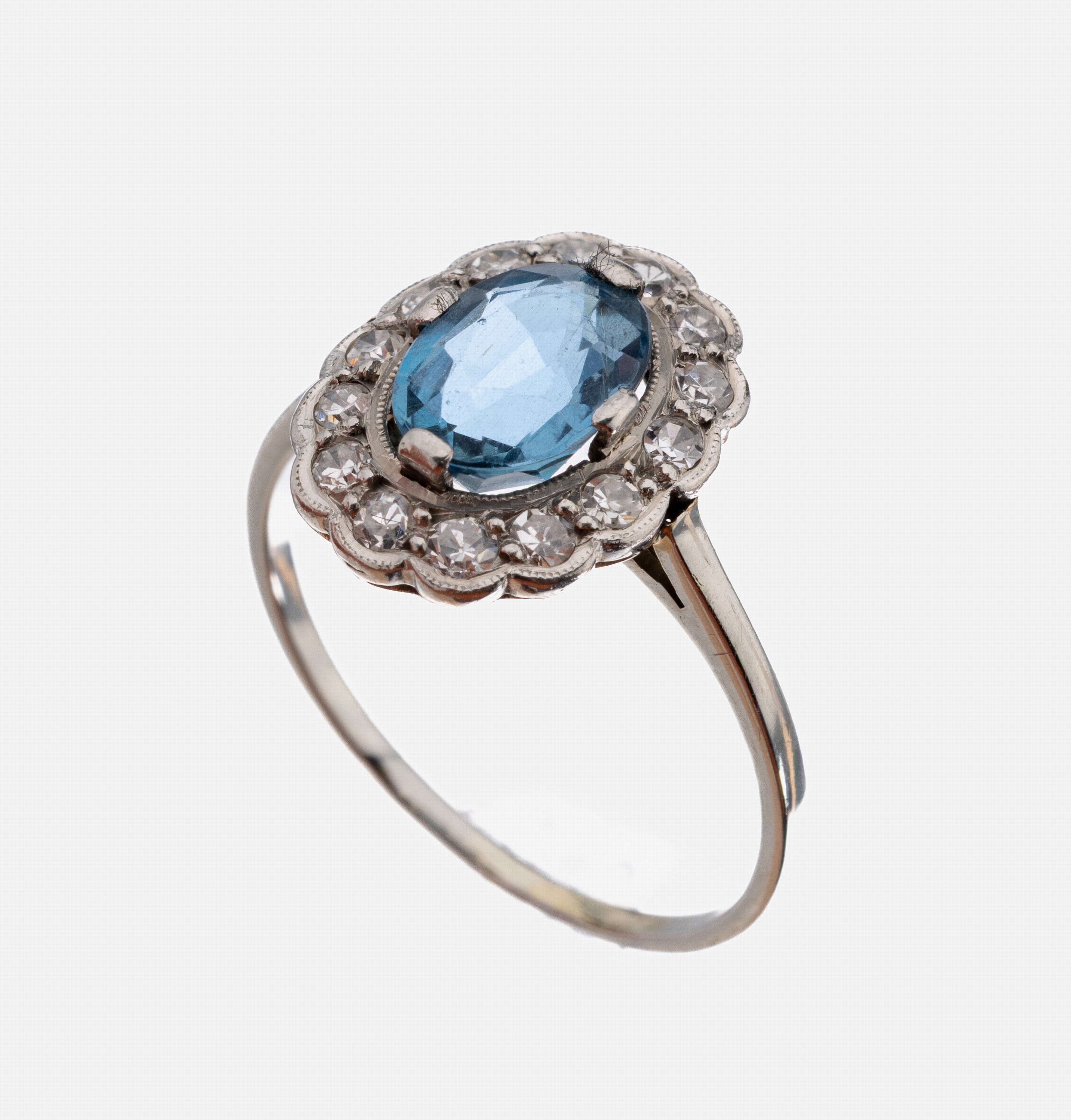 18 kt Gold Saphir-Diamant-Ring, WG 750/000 gepr., mittig erhabener ovalfacett. Saphir ca.1.15 ct, umgeben von 14 8/8-Diamanten zus. ca. 0.28 ct ...