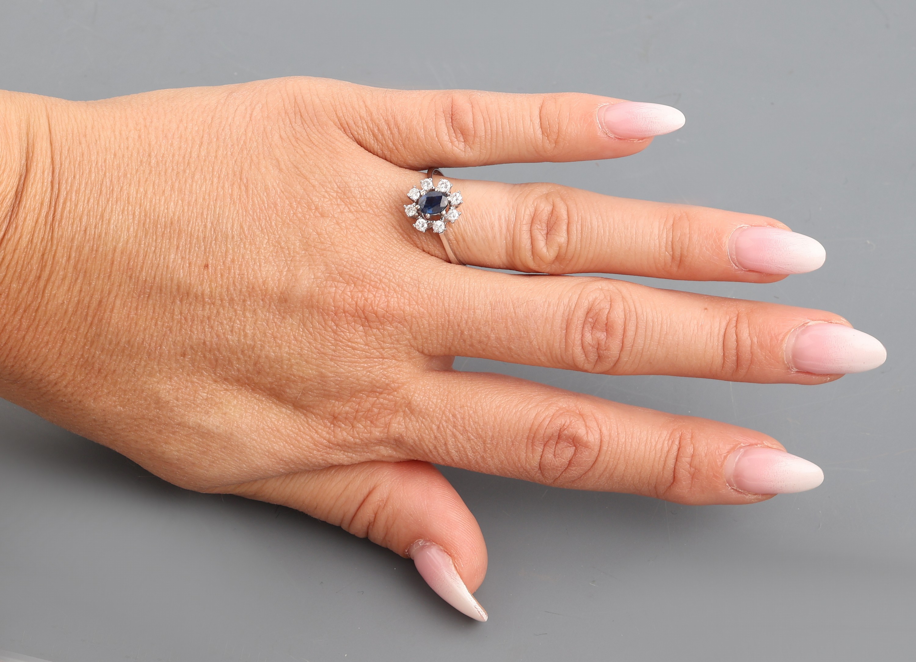 Detail d: 14 kt Gold Saphir-Brillant-Ring, WG 585/000, mittig erhaben gefasster Saphir ca. 0.45 ct, umgeben von 8 Brillanten zus. ca. 0.32 ct Weiß/p, RW 59, ...