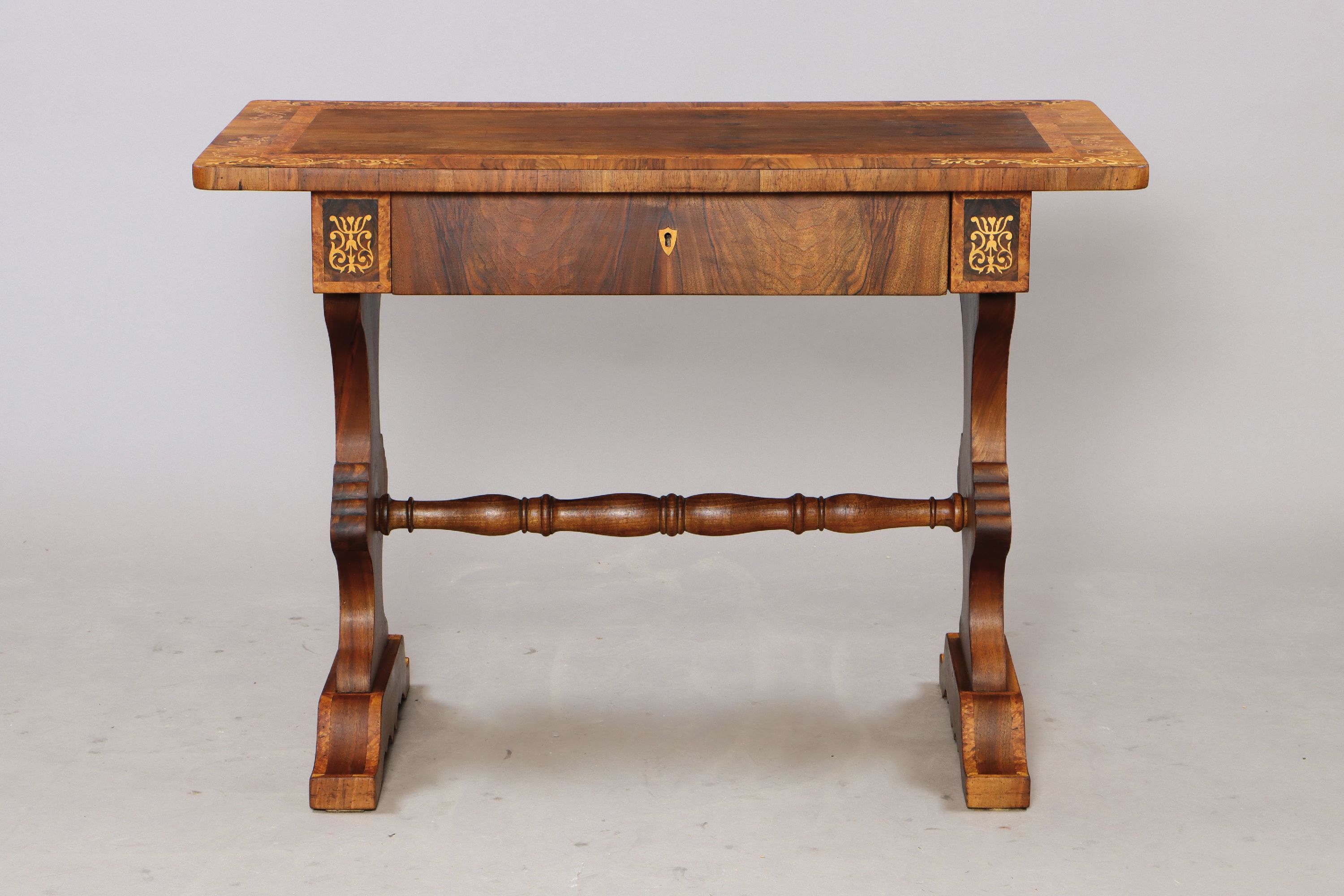 Biedermeier Schreibtisch, süddeutsch, um 1830/50, Nußbaumfurnier z.T. massiv, eine Schublade, gedrechselte Mittelstange, aufwendig intarsiert aus ...