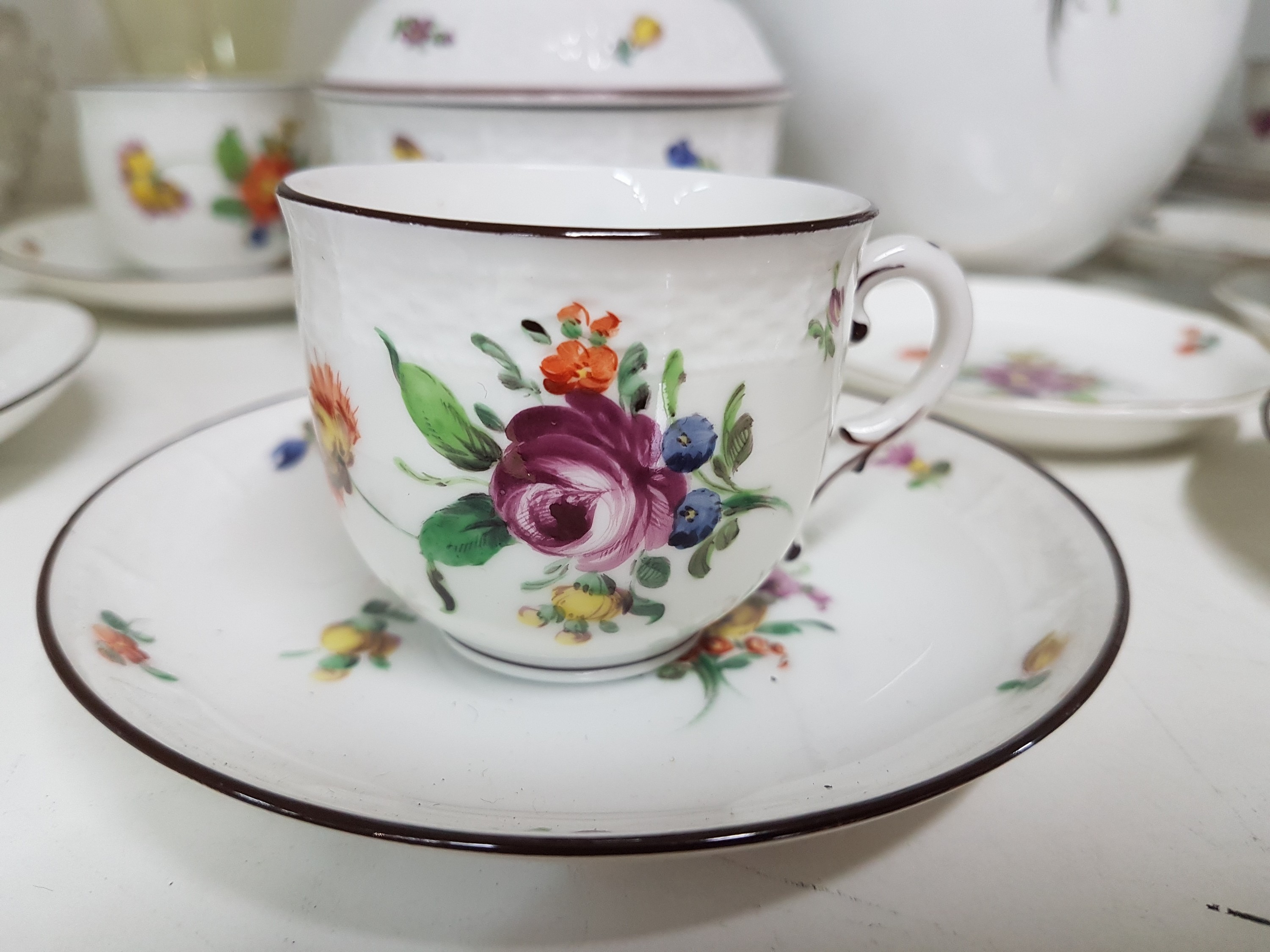 Detail b: Mokka- bzw. Espressoservice, Nymphenburg, um 1920, Porzellan, mit bunter Malerei von Blumenbuketts und gestreuten Blumen, brauner Rand, Kanne, ...