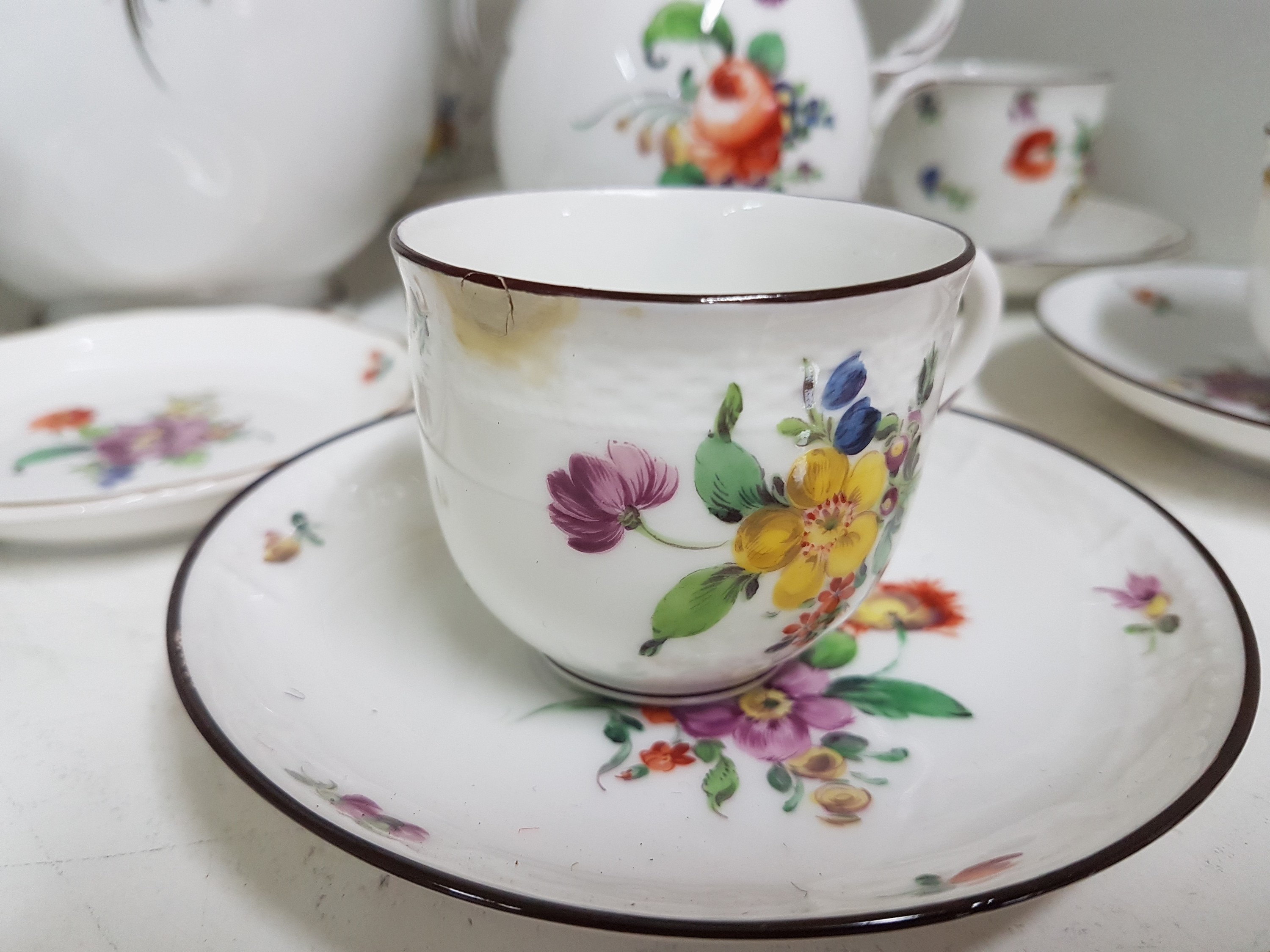 Detail c: Mokka- bzw. Espressoservice, Nymphenburg, um 1920, Porzellan, mit bunter Malerei von Blumenbuketts und gestreuten Blumen, brauner Rand, Kanne, ...