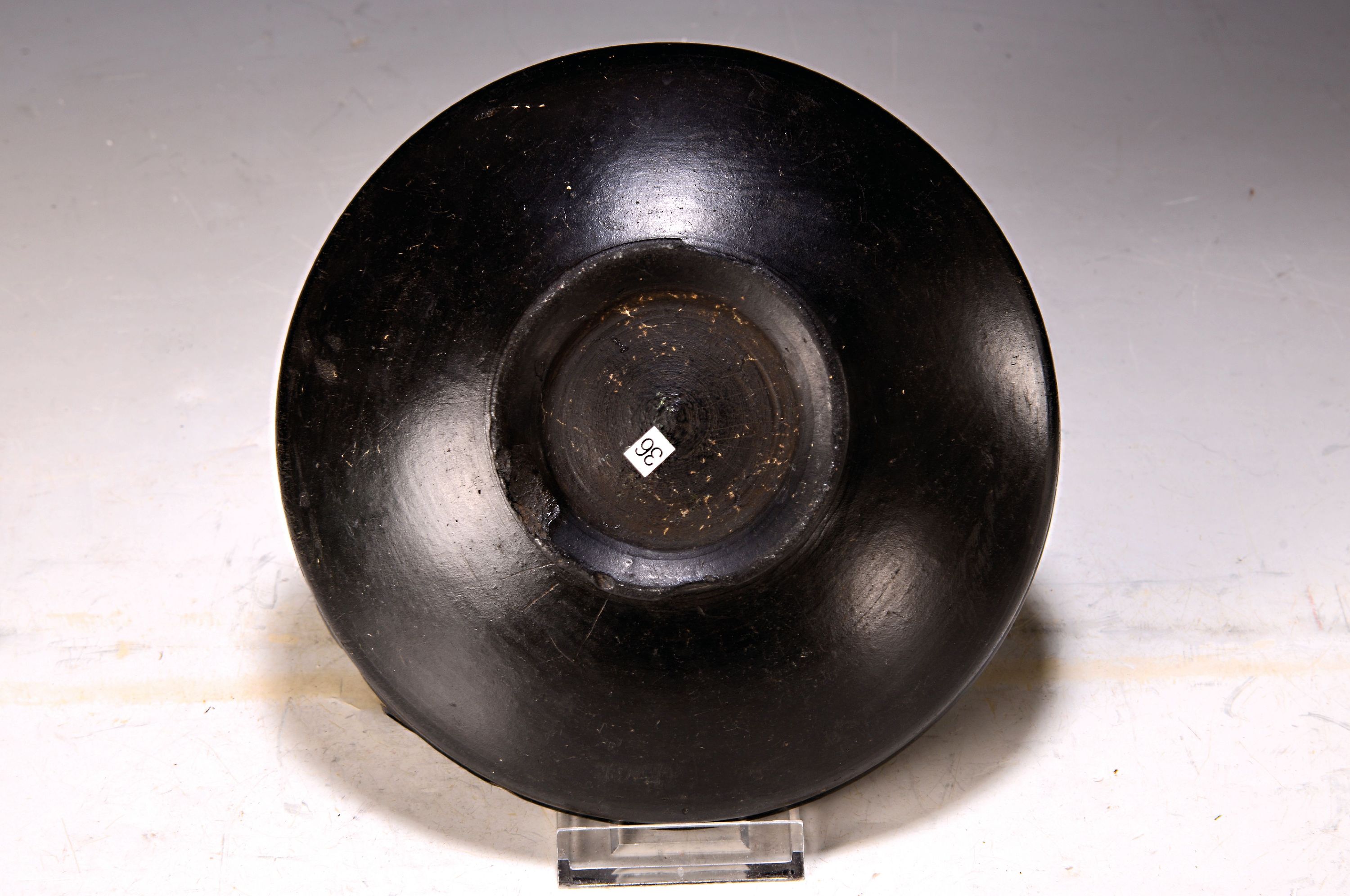 Detail a: Etruskische Bucchero Schale, 5./6.Jh., schwarz gebrannte Keramik, mehrfach bestoßen, alte Durchbohrung, auf rundem Stand, D. 19 cm, Provenienz: ...