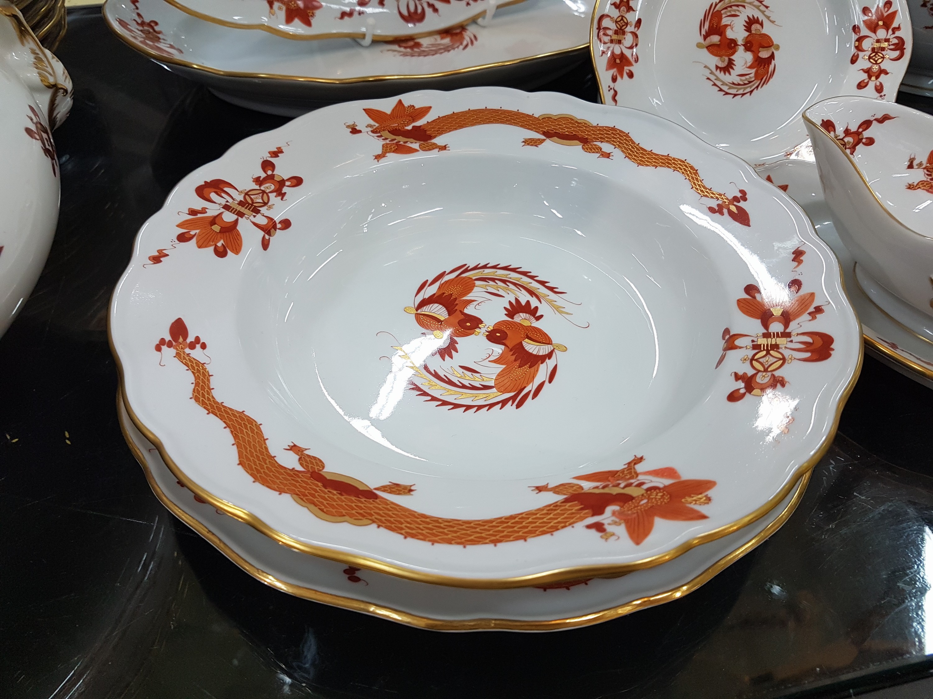 Detail b: Speiseservice, Meissen, 20. Jh., 1. Wahl, Dekor roter Hofdrache goldschattiert, 11 flache Teller, 3 tiefe Teller (davon einer 2. Wahl), 6 ...
