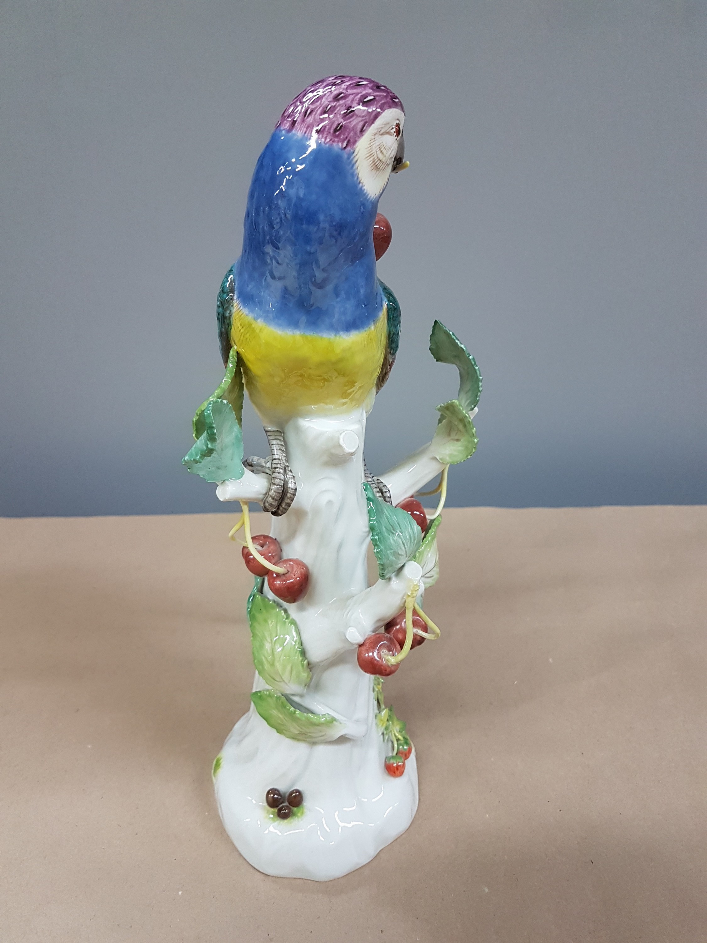 Detail b: Porzellanfigur, Meissen, 20. Jh., Papagei auf Baumstumpf mit Kirschen, bunt naturalistisch bemalt, H. ca. 31cm