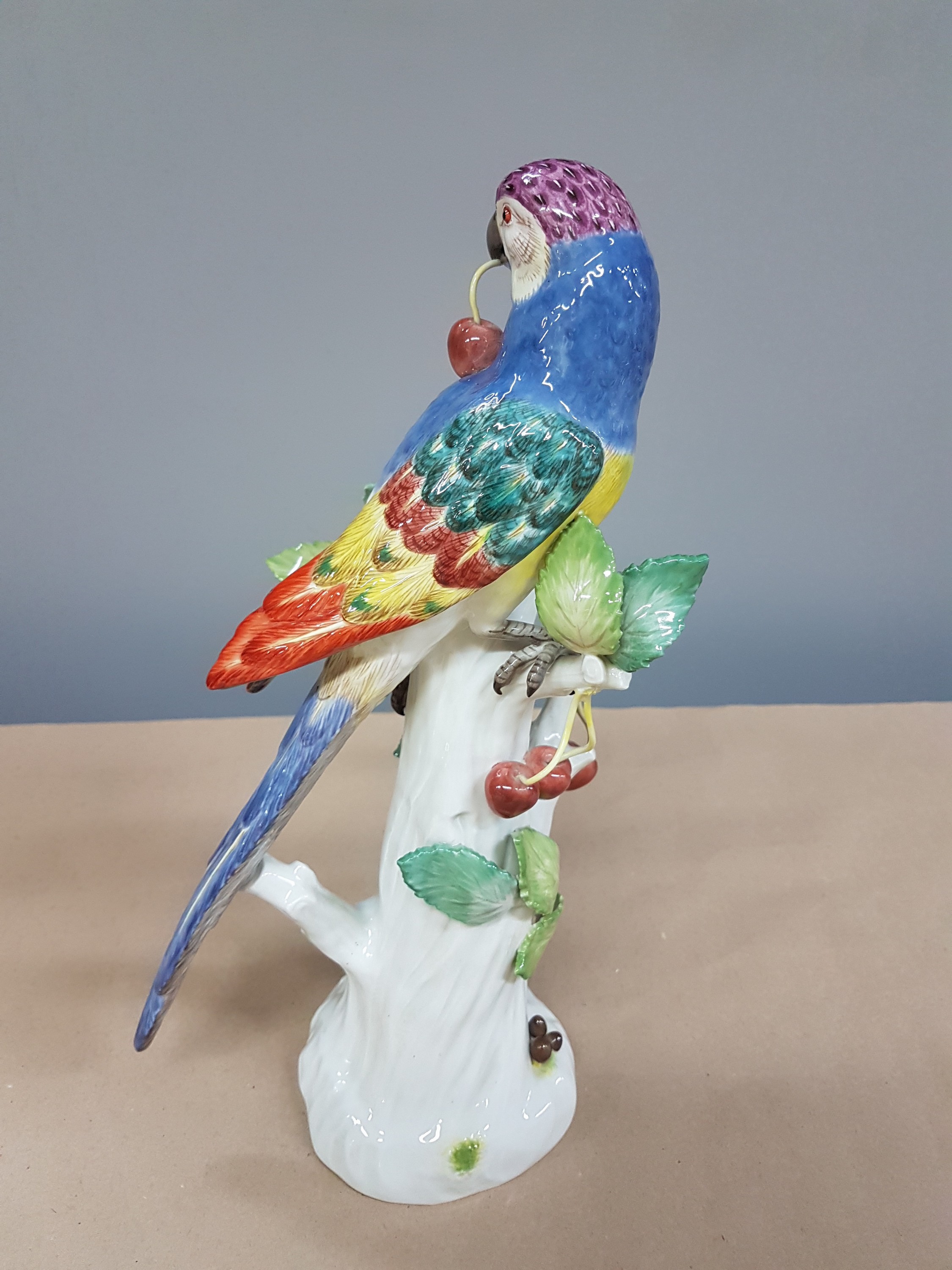 Detail c: Porzellanfigur, Meissen, 20. Jh., Papagei auf Baumstumpf mit Kirschen, bunt naturalistisch bemalt, H. ca. 31cm
