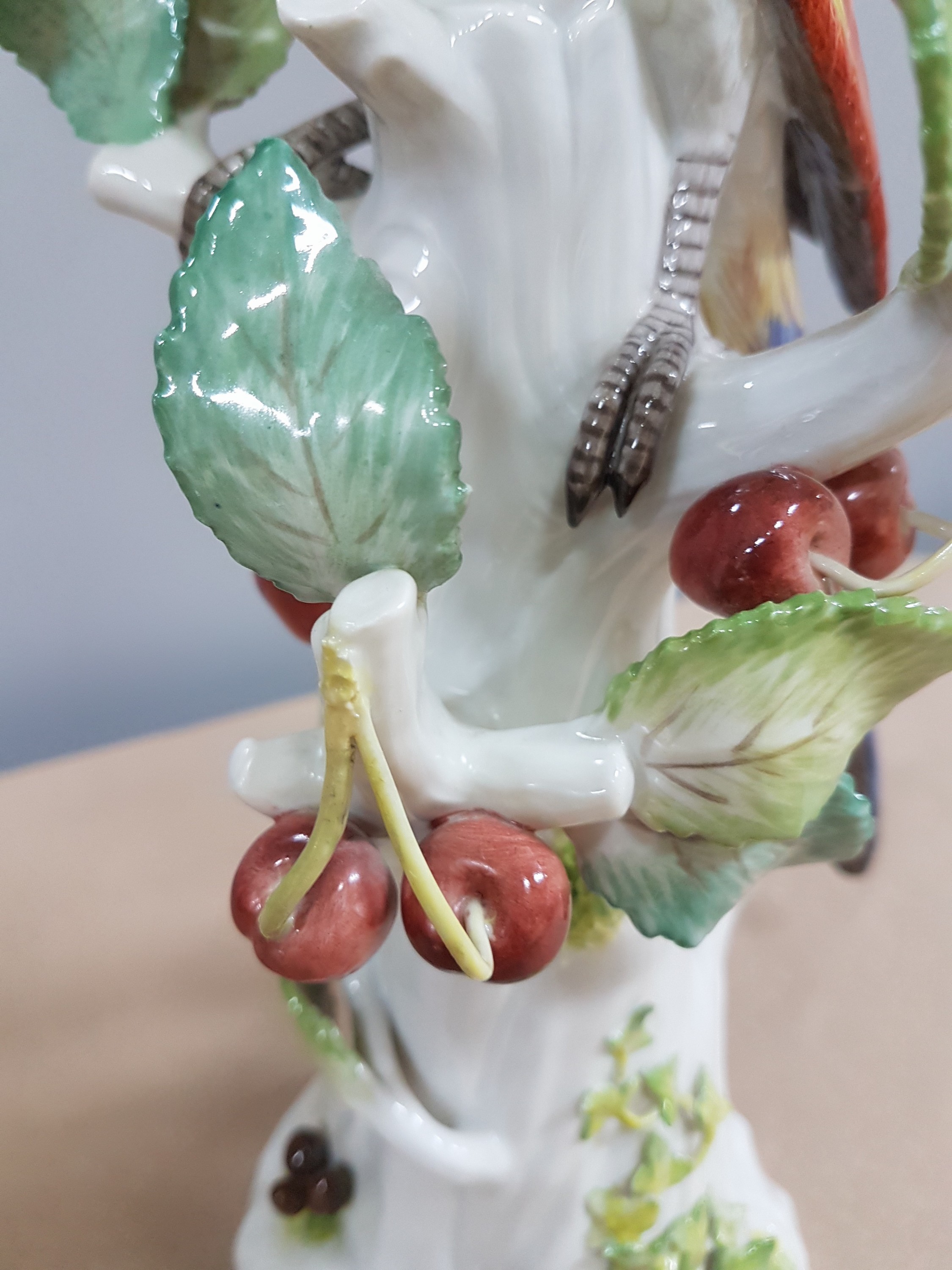 Detail g: Porzellanfigur, Meissen, 20. Jh., Papagei auf Baumstumpf mit Kirschen, bunt naturalistisch bemalt, H. ca. 31cm
