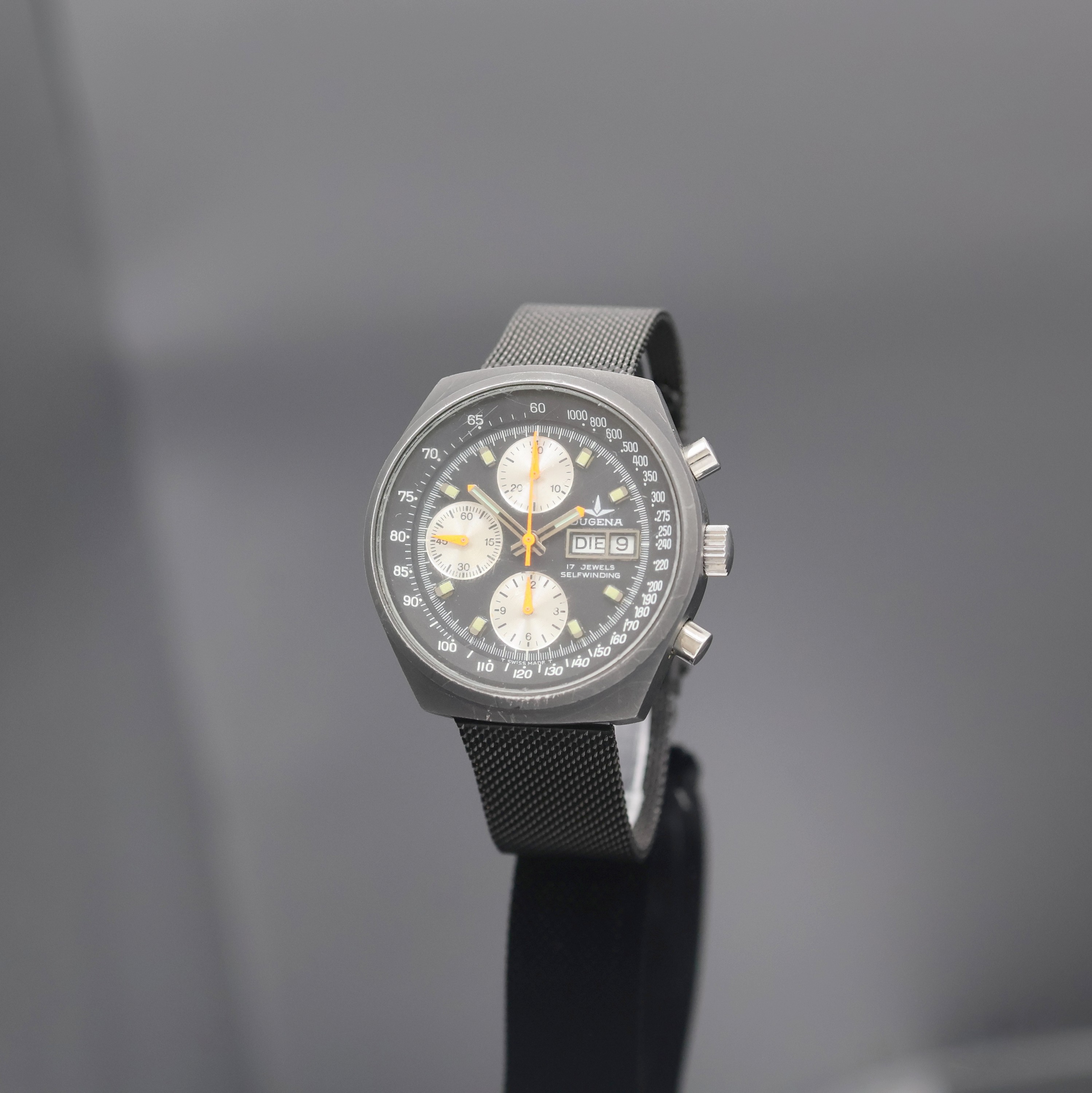 DUGENA Herrenchronograph, Schweiz um 1980, Automatik, 2-teil., geschwärztes Edelstahlgeh., verschr. Boden, schwarzes Milanaiseband, schwarzes ...