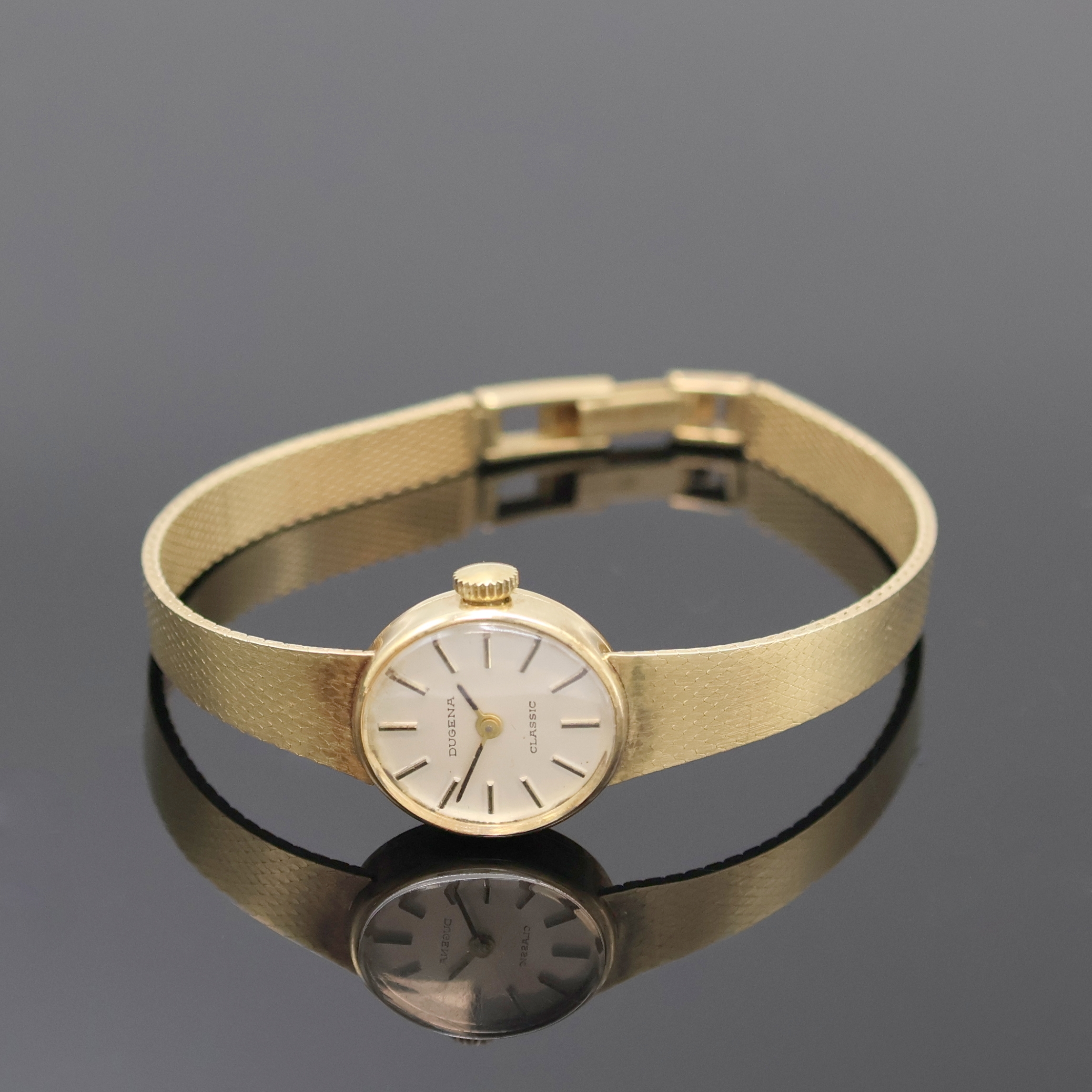 DUGENA Classic Damenarmbanduhr in GG 585/000, Schweiz um 1965, Handaufzug, Goldband, Boden aufgedr., silb. Zifferbl. m. aufges. Std.-Ind., geschw. ...