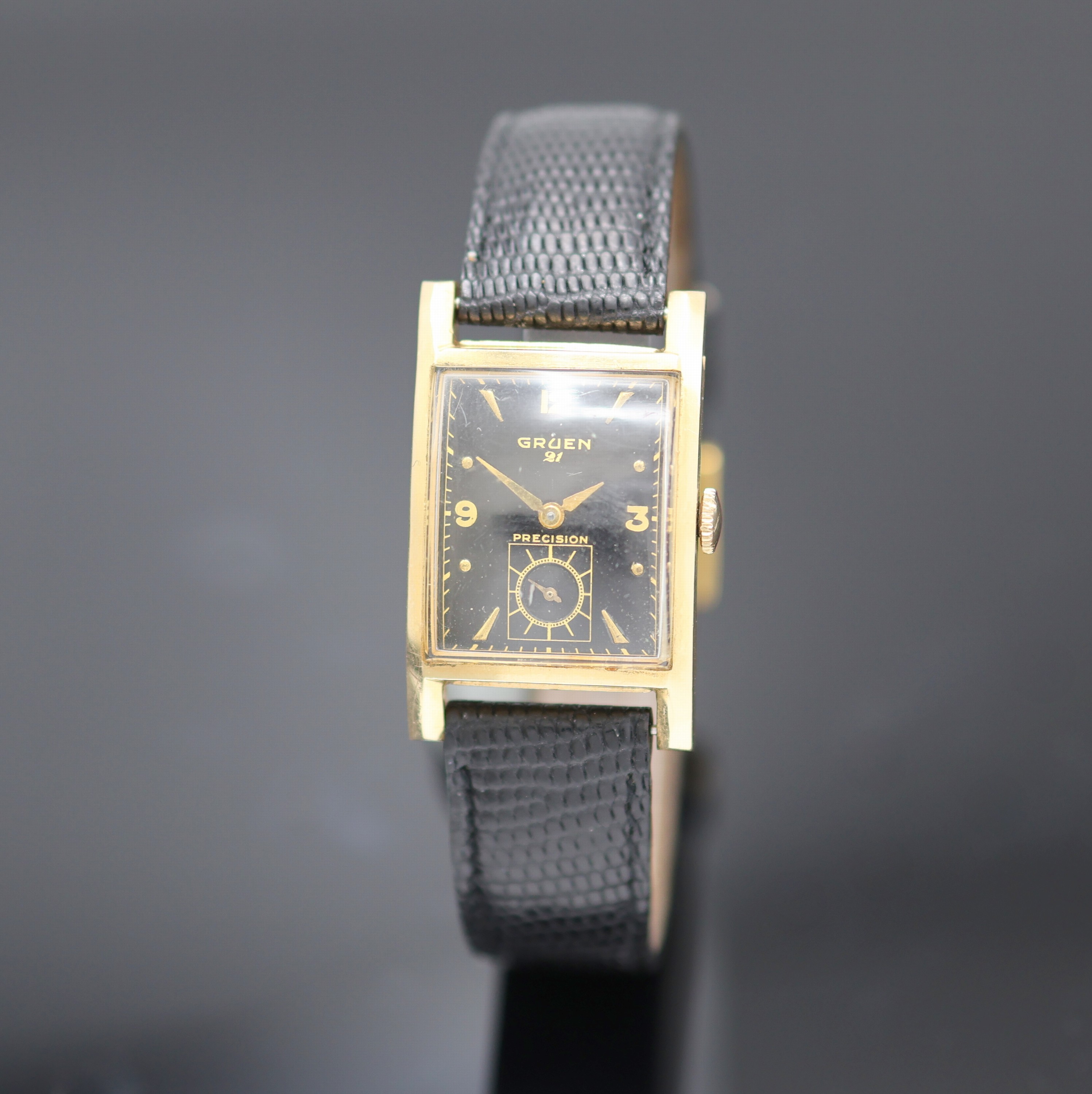 GRUEN Precision Armbanduhr in GG 585/000, USA um 1945, Handaufzug, Boden m. Monogramm aufgedr., schwarzes Zifferbl. m. arab. Zahlen u. gold. ...