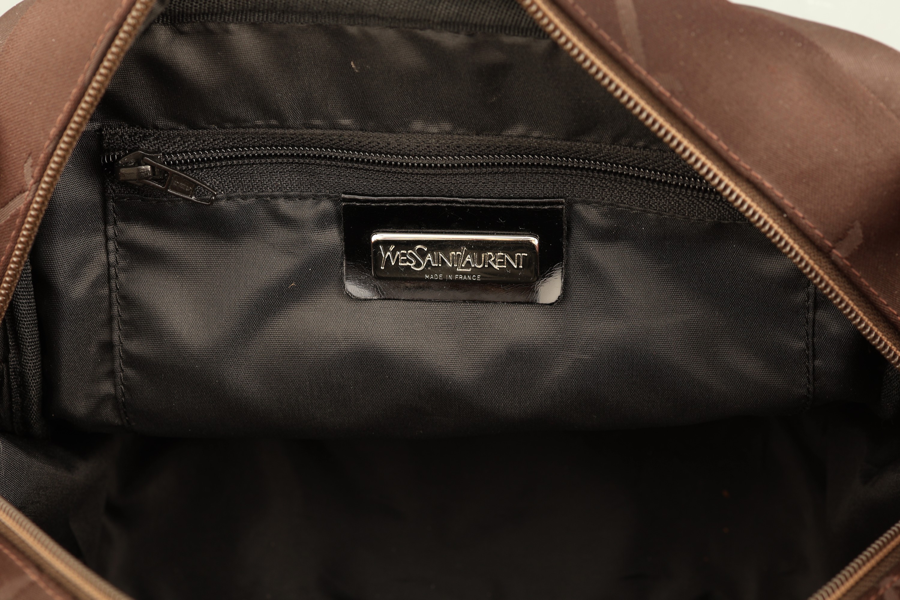 Detail a: YVES SAINT LAURENT Handtasche, braunes Nylon, changierend, Monturen und YSL Anhänger Metall vers., 2 Tragehenkel (besch.), innen schwarzer Stoff, ...