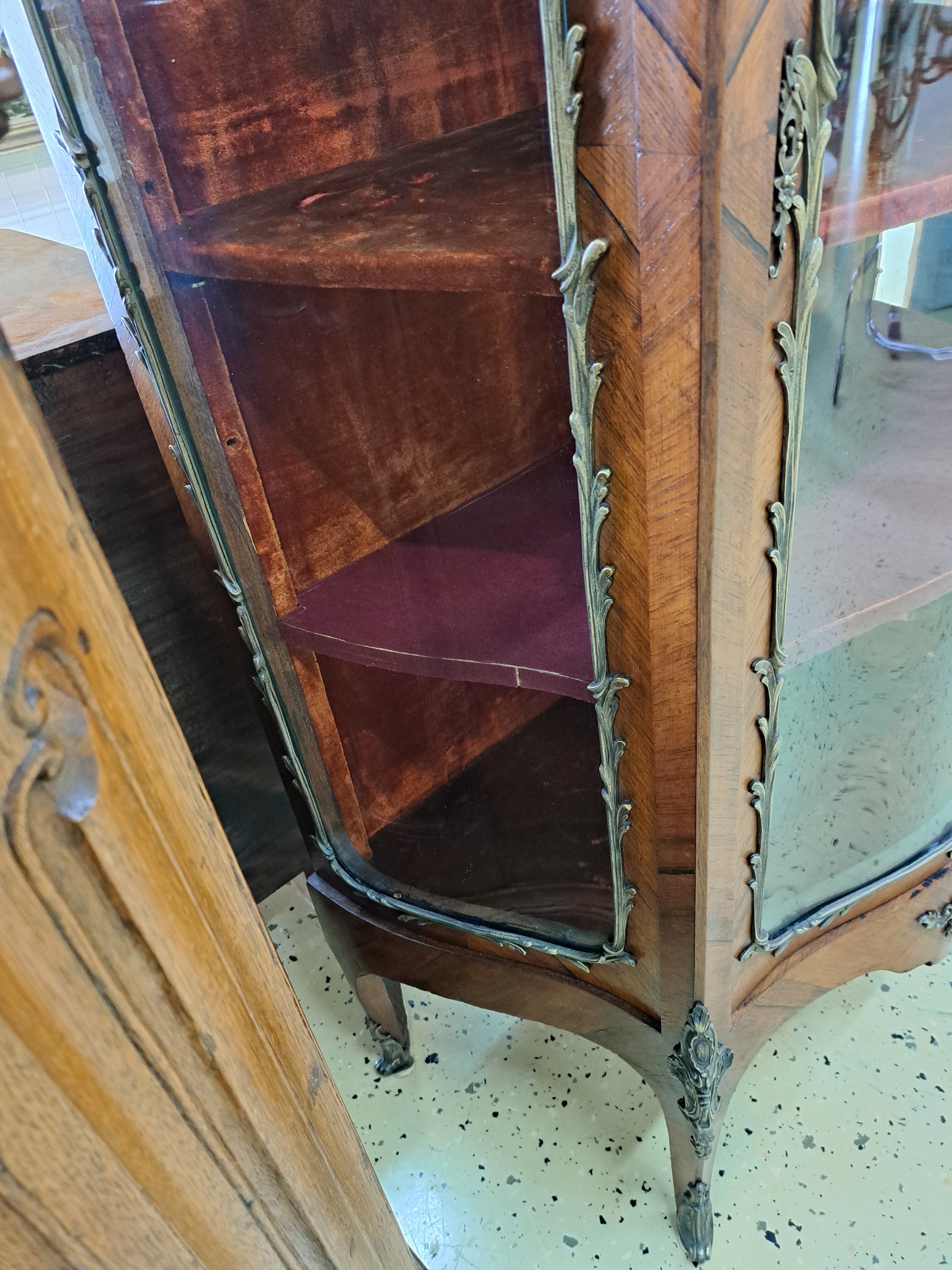 Detail b: Vitrine, Frankreich, um 1860, Nußbaum, Front und Seiten stark geschwungen mit orig. gewalztem Glas, eingefaßt mit Messing im Ränderdekor, Kanten ...