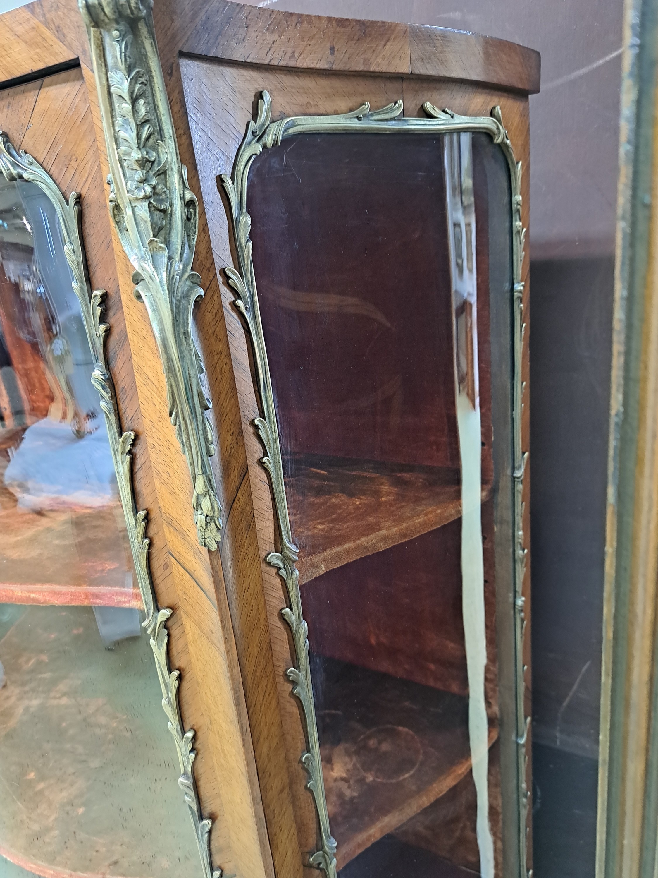Detail c: Vitrine, Frankreich, um 1860, Nußbaum, Front und Seiten stark geschwungen mit orig. gewalztem Glas, eingefaßt mit Messing im Ränderdekor, Kanten ...