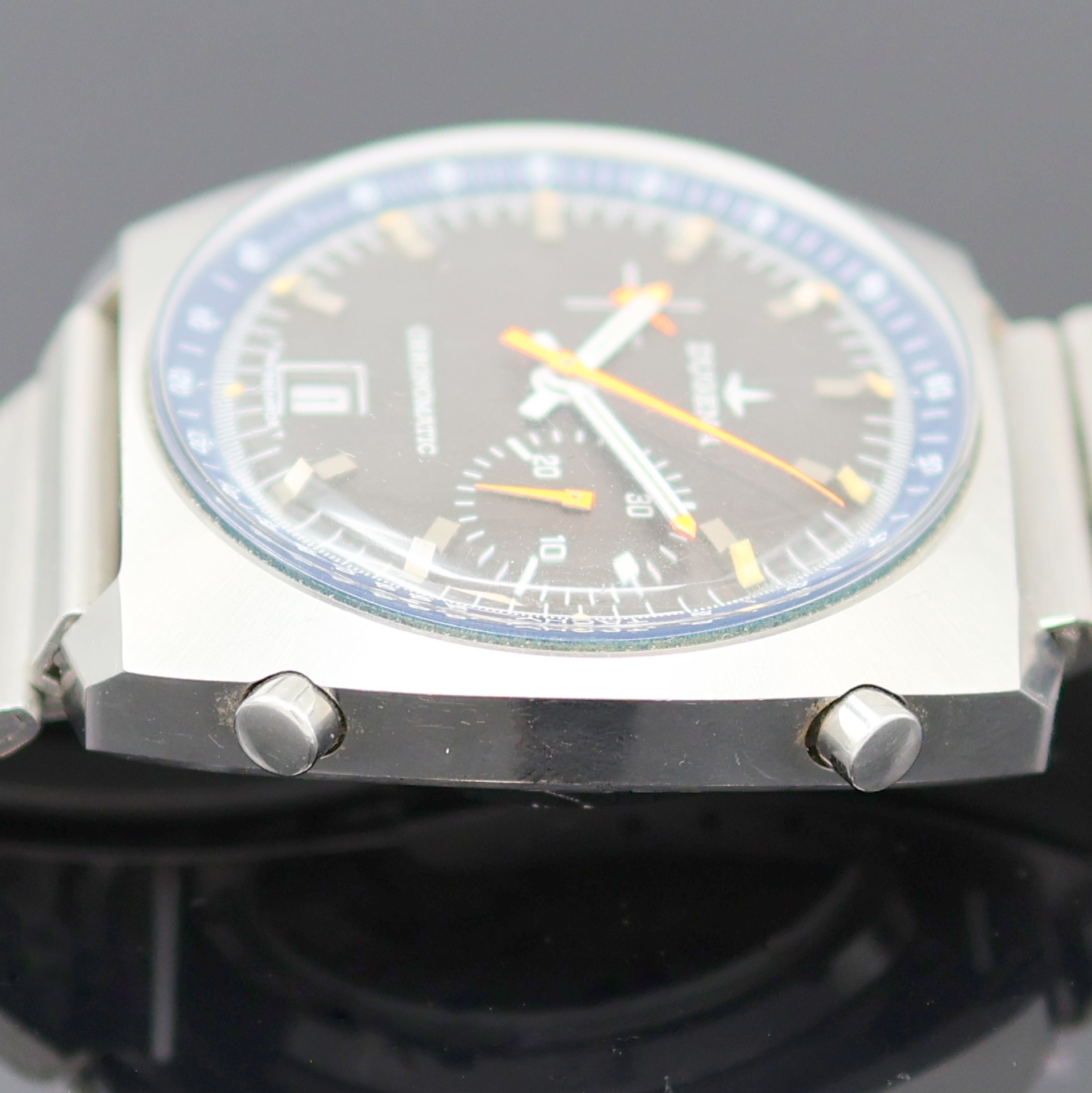 Detail e: DUGENA Chronomatic Herrenchronograph in Stahl Kaliber 15, Schweiz um 1975, Automatik, kissenförm. Geh., verschr. Glasboden später, am passenden ...