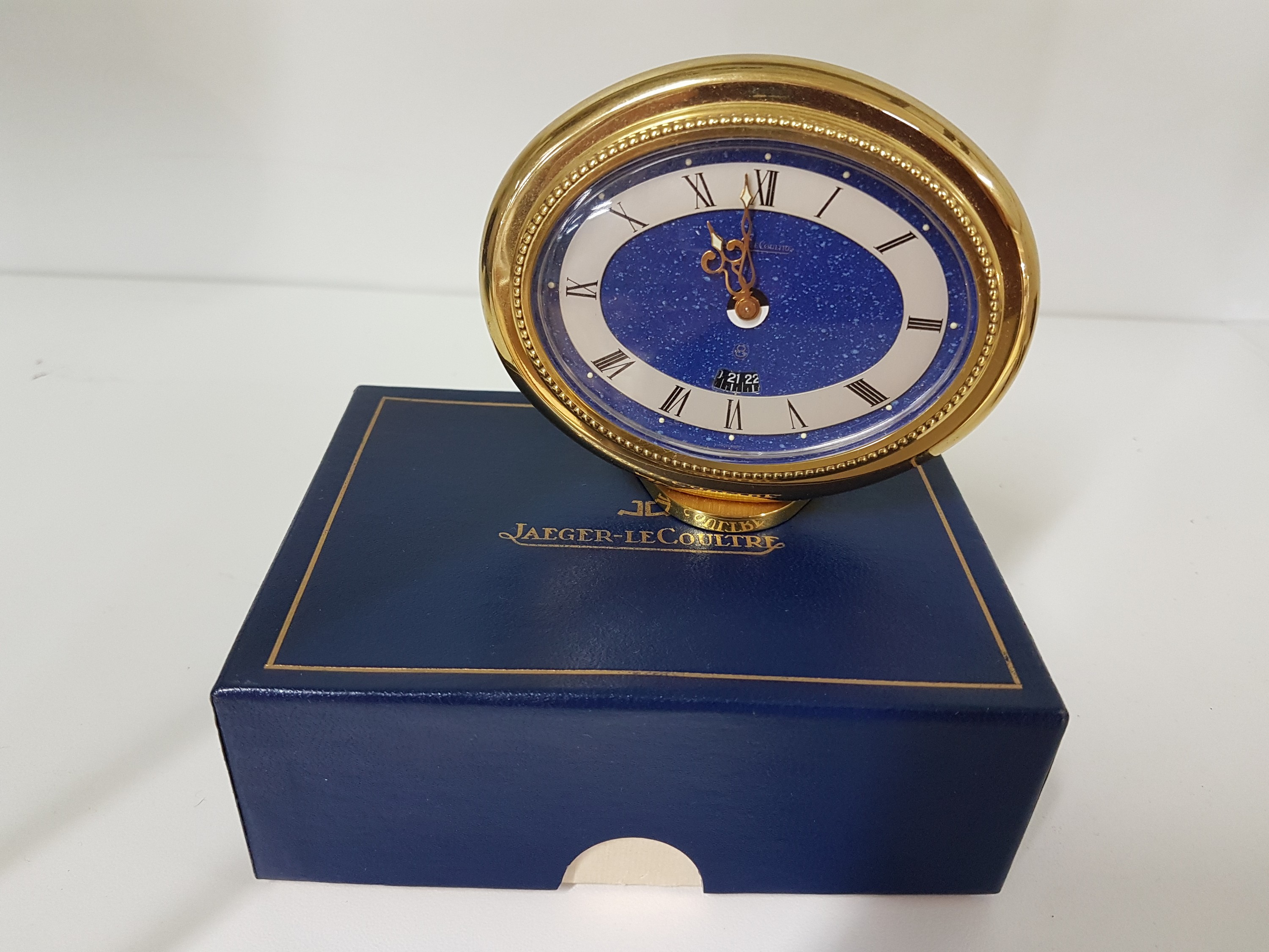 Detail a: Tischuhr Jaeger-LeCoultre, um 1970, vergoldetes Gehäuse, oval liegend, Weckzeit- Fenster über Ziffer 6, mit Tag- und Nachtanzeige im Stundenzeiger, ...