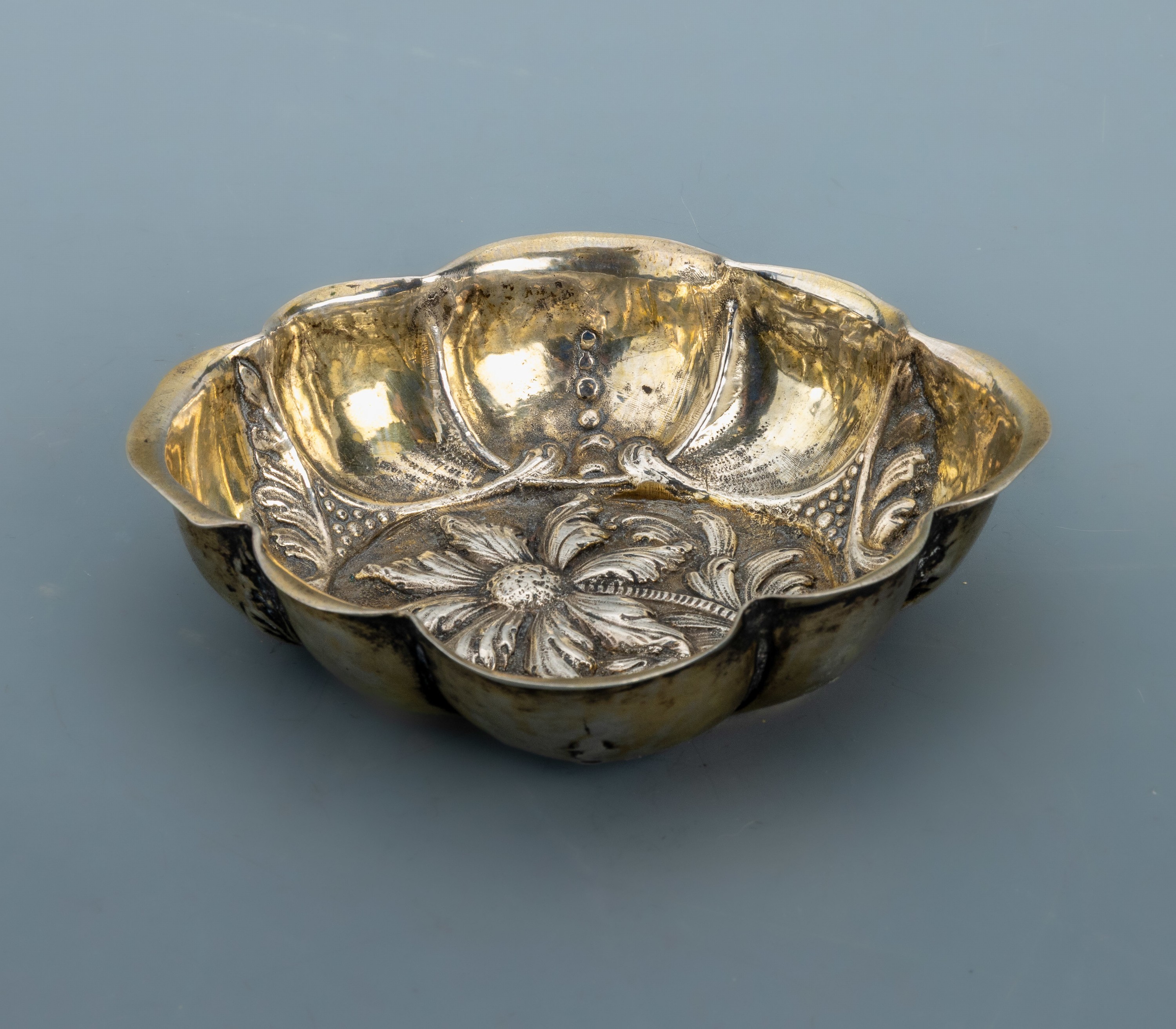 Detail a: Branntweinschale, Hanau um 1880-90, 835er Silber, innen part. verg., nach älterem Vorbild, Treibarbeit, Darstellung von Blüten und Blättern, ...
