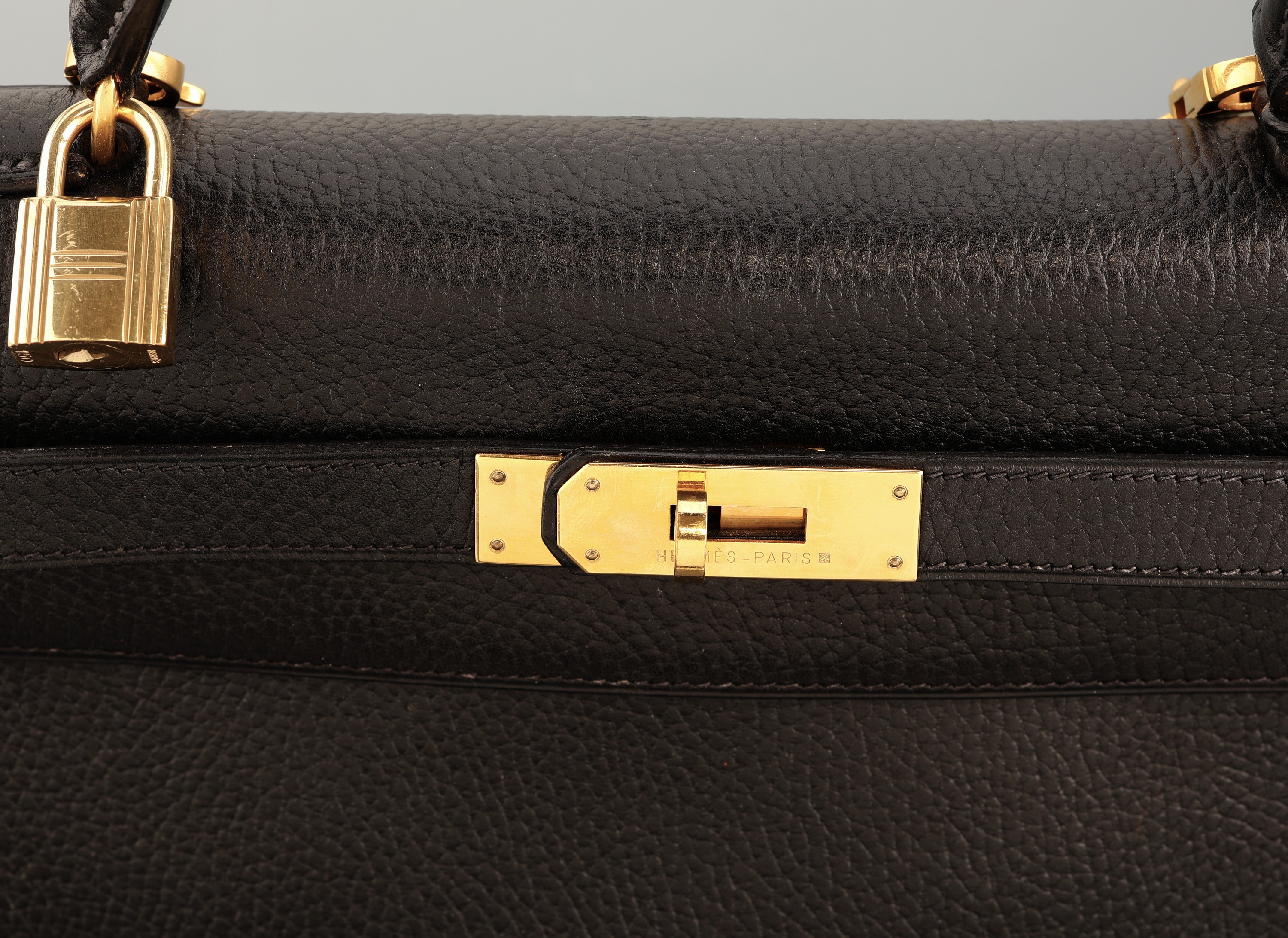 Detail d: HERMES Kelly Bag, 1983, schwarzes Togo Leder, orig. Clochette und Schloss, Trageriemen, Gebr.-Spuren, ca. 34 x 13 x 24 cm