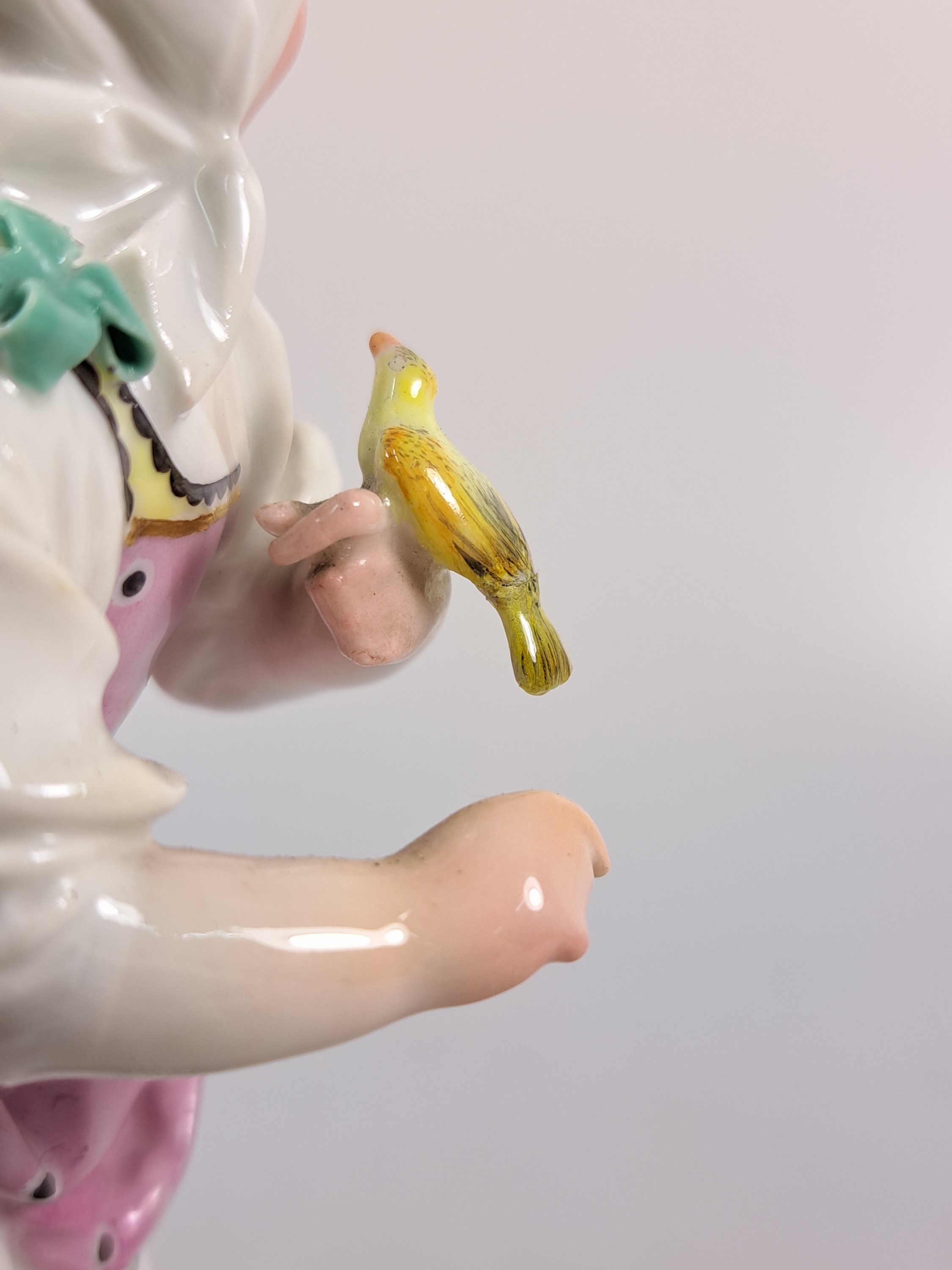 Detail i: Porzellanfigur, Höchst, um 1770, Mädchen mit Kopftuch und Vogel, bunt bemalt, restauriert, H. 18.3 cm