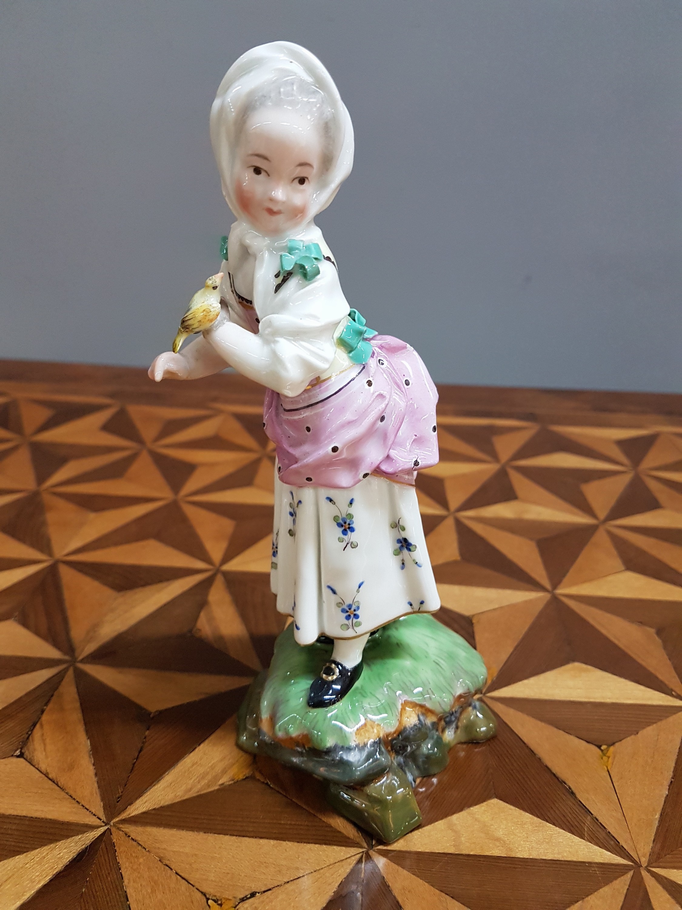 Detail k: Porzellanfigur, Höchst, um 1770, Mädchen mit Kopftuch und Vogel, bunt bemalt, restauriert, H. 18.3 cm