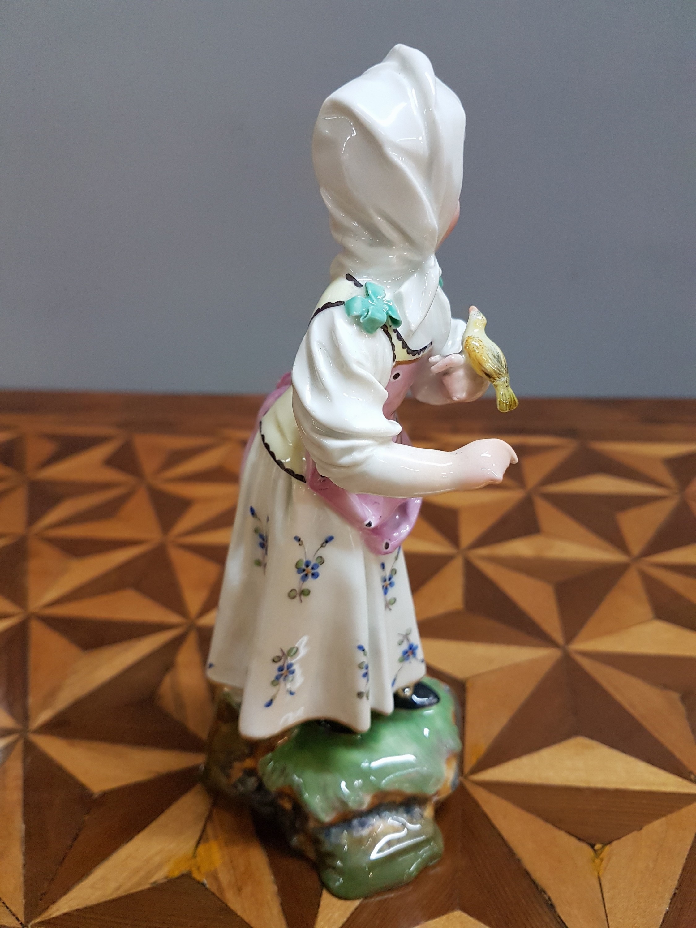 Detail l: Porzellanfigur, Höchst, um 1770, Mädchen mit Kopftuch und Vogel, bunt bemalt, restauriert, H. 18.3 cm