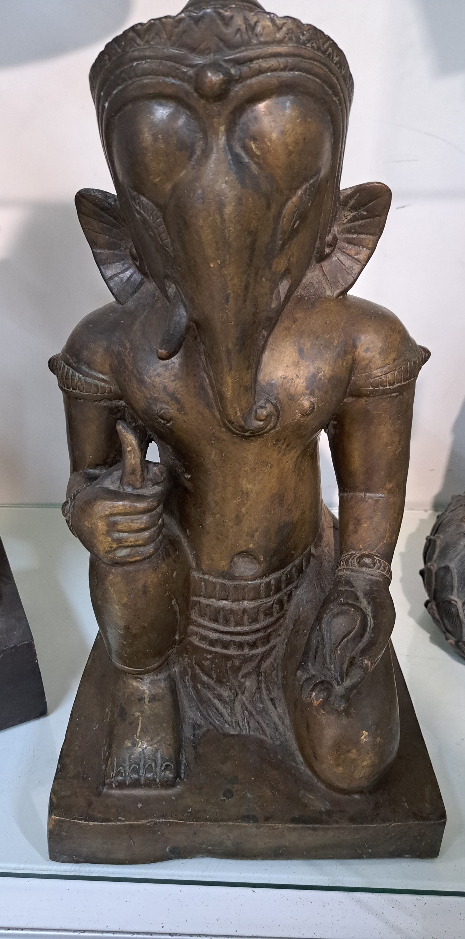 Detail a: Große Bronzefigur, Ganesha, Khmer-Stil, wohl 19. Jh., kniende Darstellung, in einer Hand Shankha (Muschel) in der anderen Hand den abgebrochenen ...