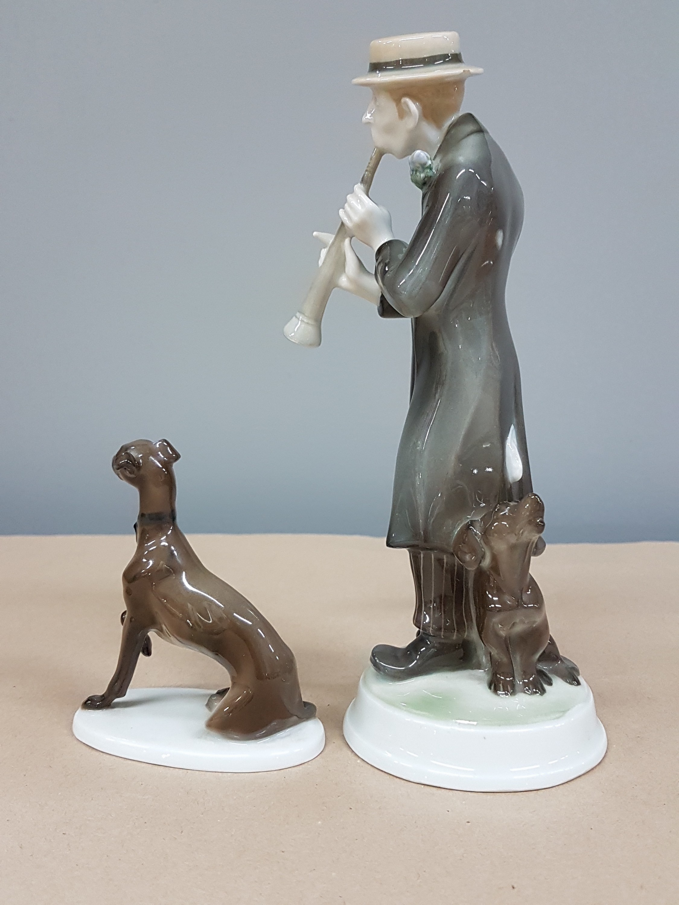 Detail d: Zwei Figuren Rosenthal, Kriegsmarke und, um 1920, Klarinettenspieler, 1914-18, am Hut min. best., H. ca. 20.5 cm, dazu Jagdhund, K 289, auf ovalem ...
