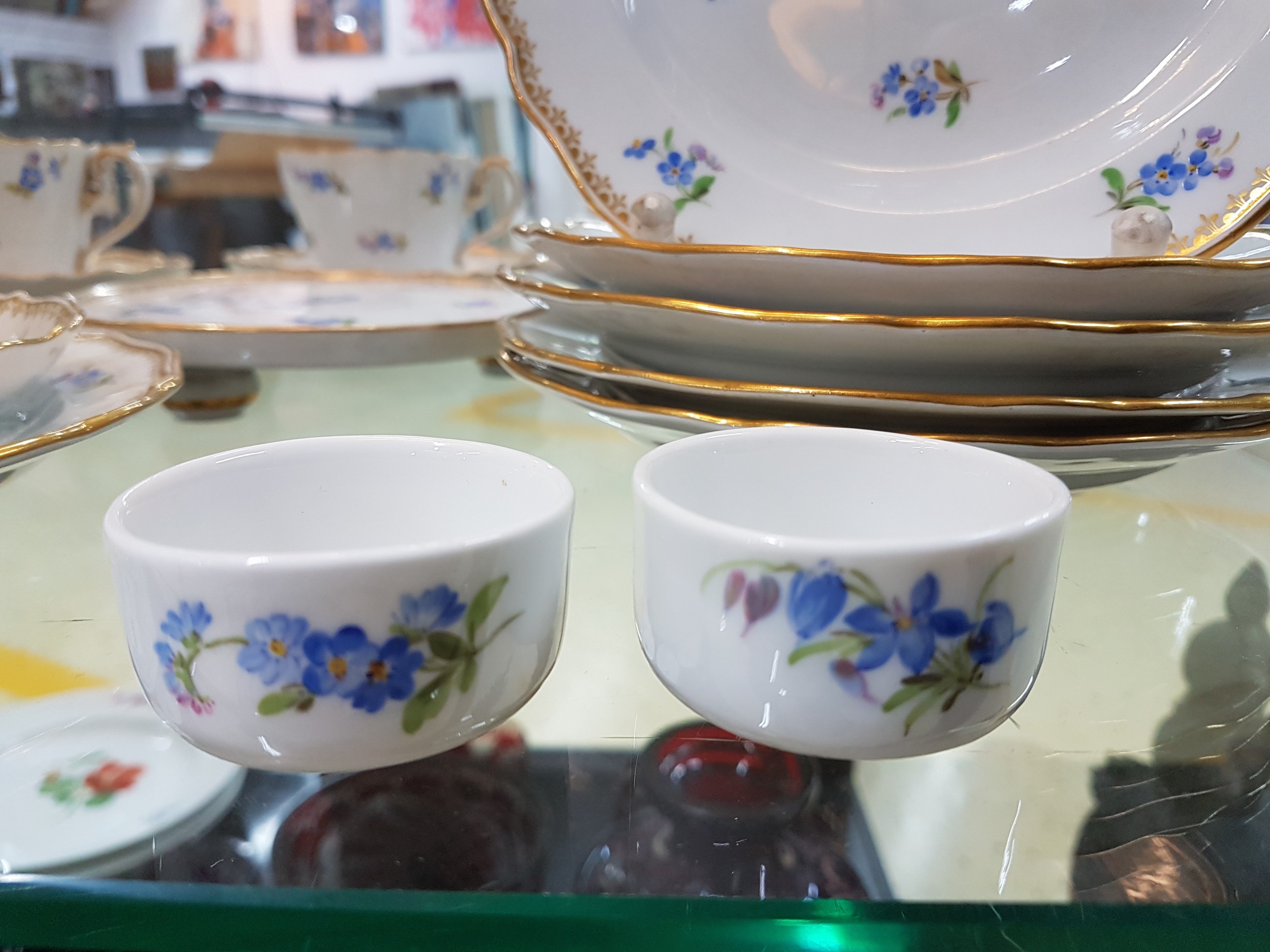 Detail d: 6 Tassen mit Untertassen, 6 Gebäckteller, Meissen, um 1900, 1. Wahl, Porzellan, but bemalt mit gestreuten Vergissmeinnicht, Goldkante, dazu ...