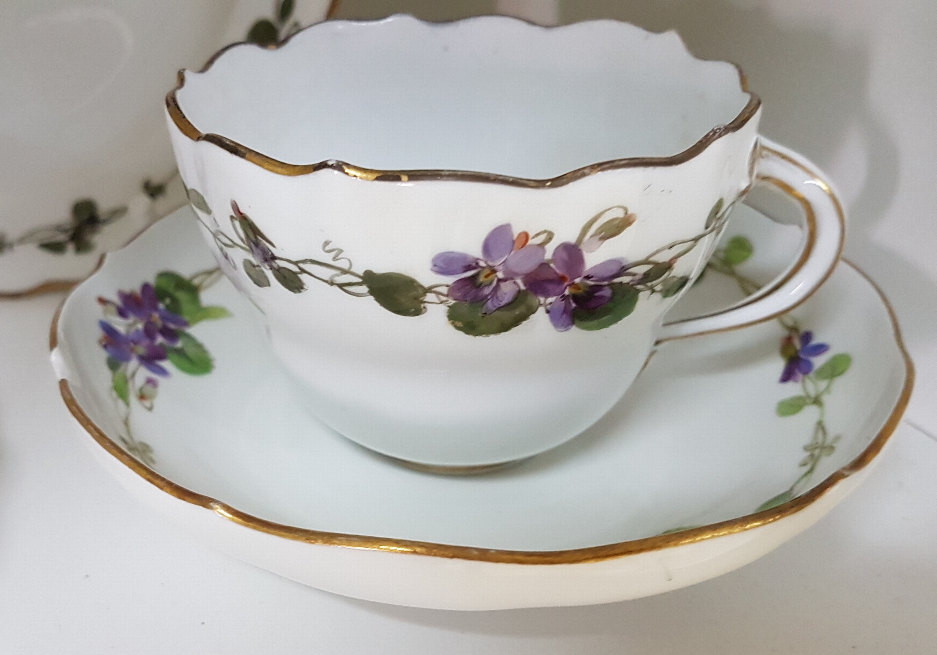 Detail c: 7 Teile Porzellan, Meissen, um 1900, 1. Wahl, mit Veilchen-Bordüren bemalt, Goldrand, 3 Tassen, 2 Untertassen, davon eine best., 2 Teller 17cm mit ...
