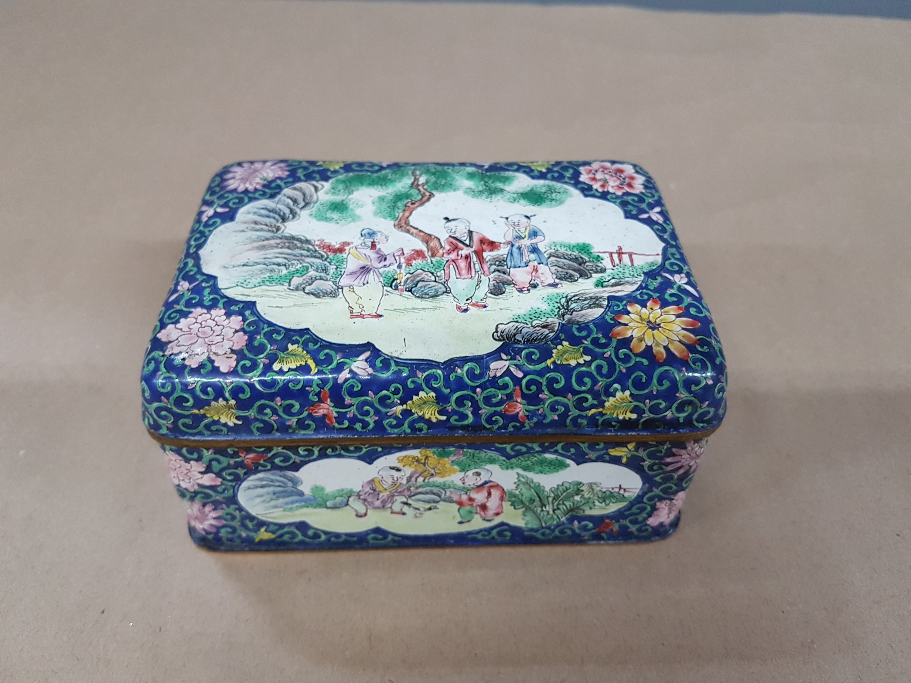 Detail a: Deckeldose, China, 20. Jh., Emailarbeit, 3 figürliche Szenen in Landschaft bemalt, zwei Kartuschen mit Blumenmalerei, ca. 6 x 12 x 9 cm
