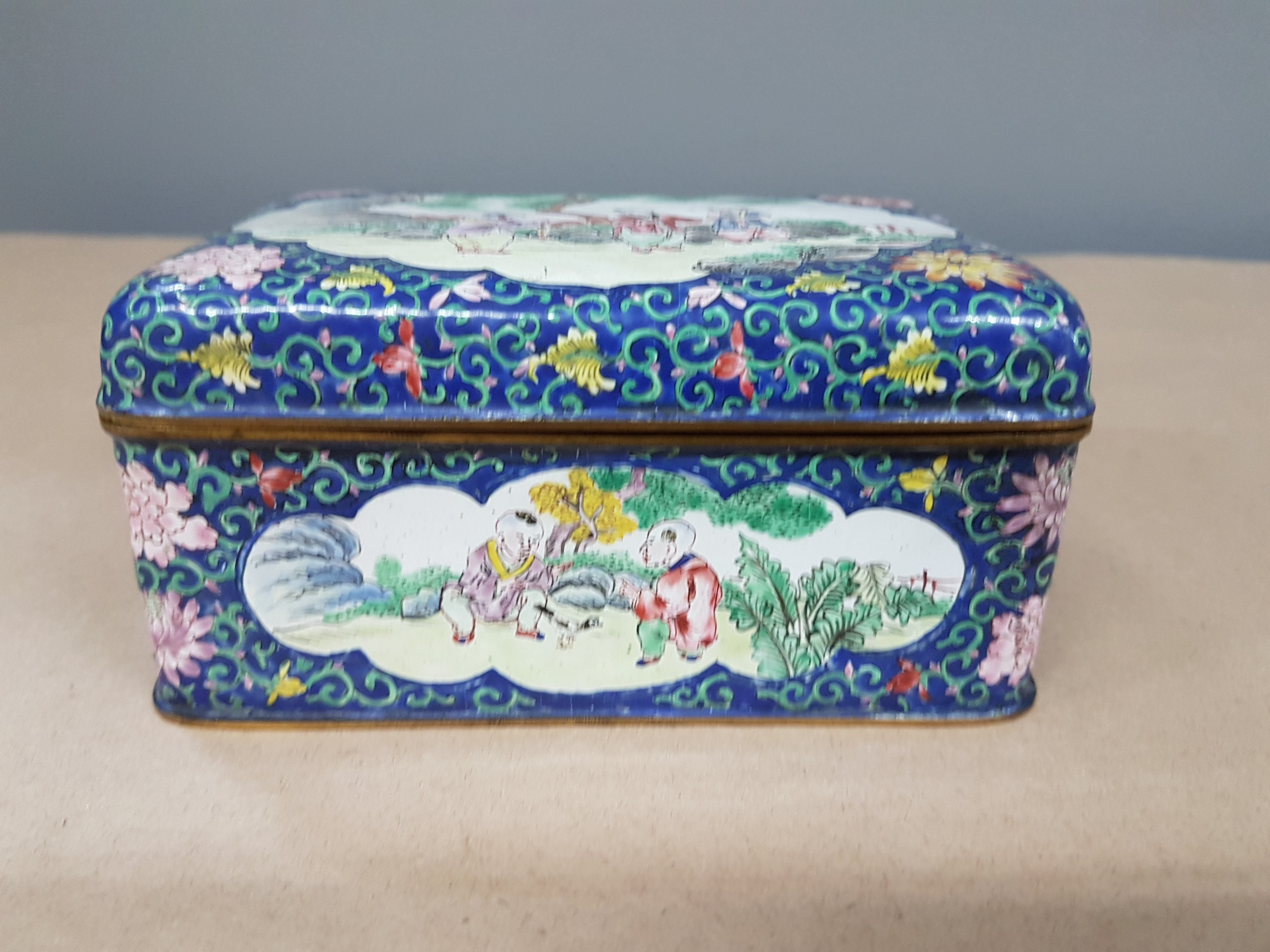 Detail b: Deckeldose, China, 20. Jh., Emailarbeit, 3 figürliche Szenen in Landschaft bemalt, zwei Kartuschen mit Blumenmalerei, ca. 6 x 12 x 9 cm