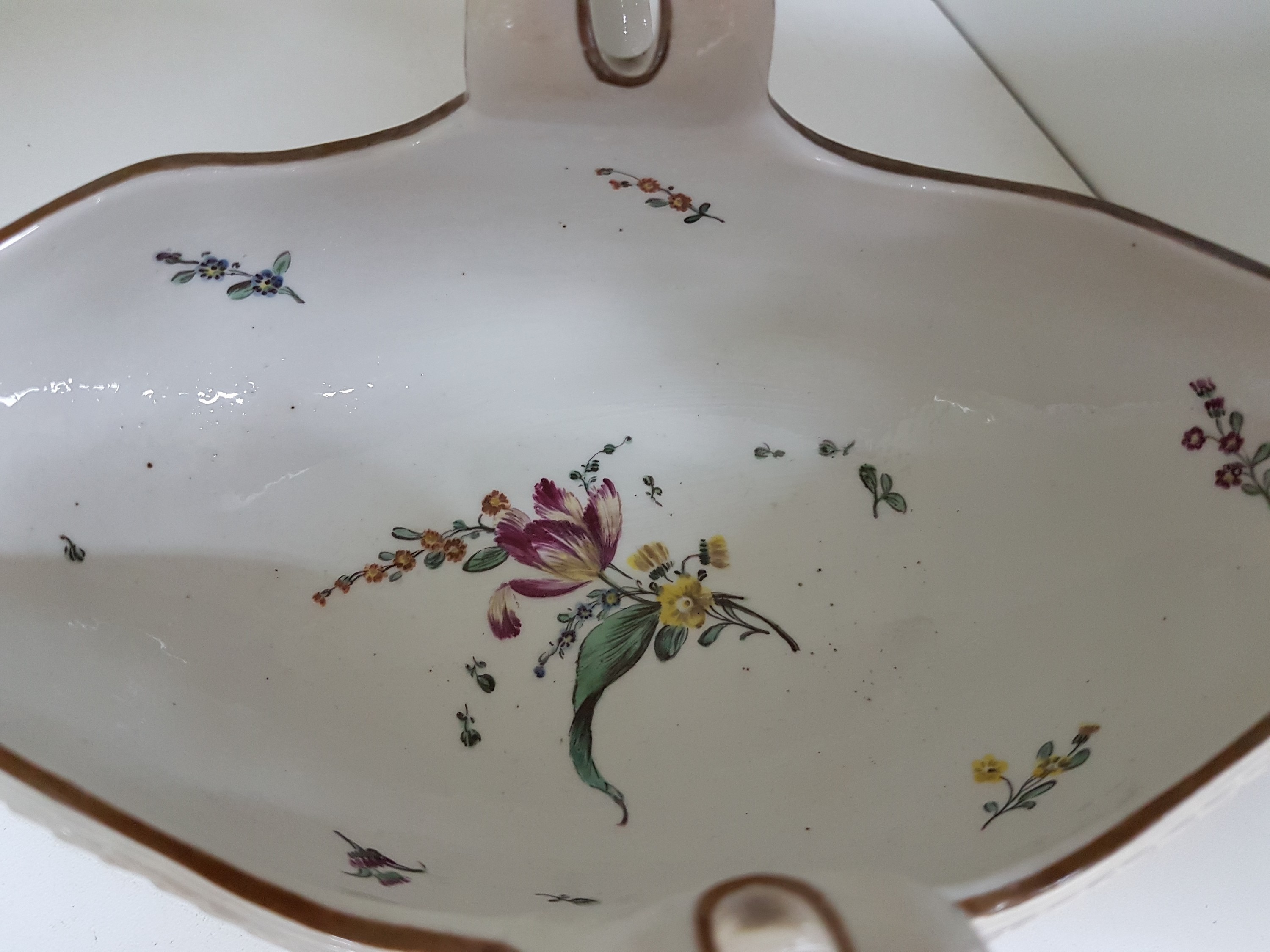 Detail e: Sauciere, Frankenthal, um 1775, gekreuzte Griffe, umlaufendes Lorbeerband um Fuß und Rand, ockerfarbener Rand, innen mit Blumengebinde und gestreute ...
