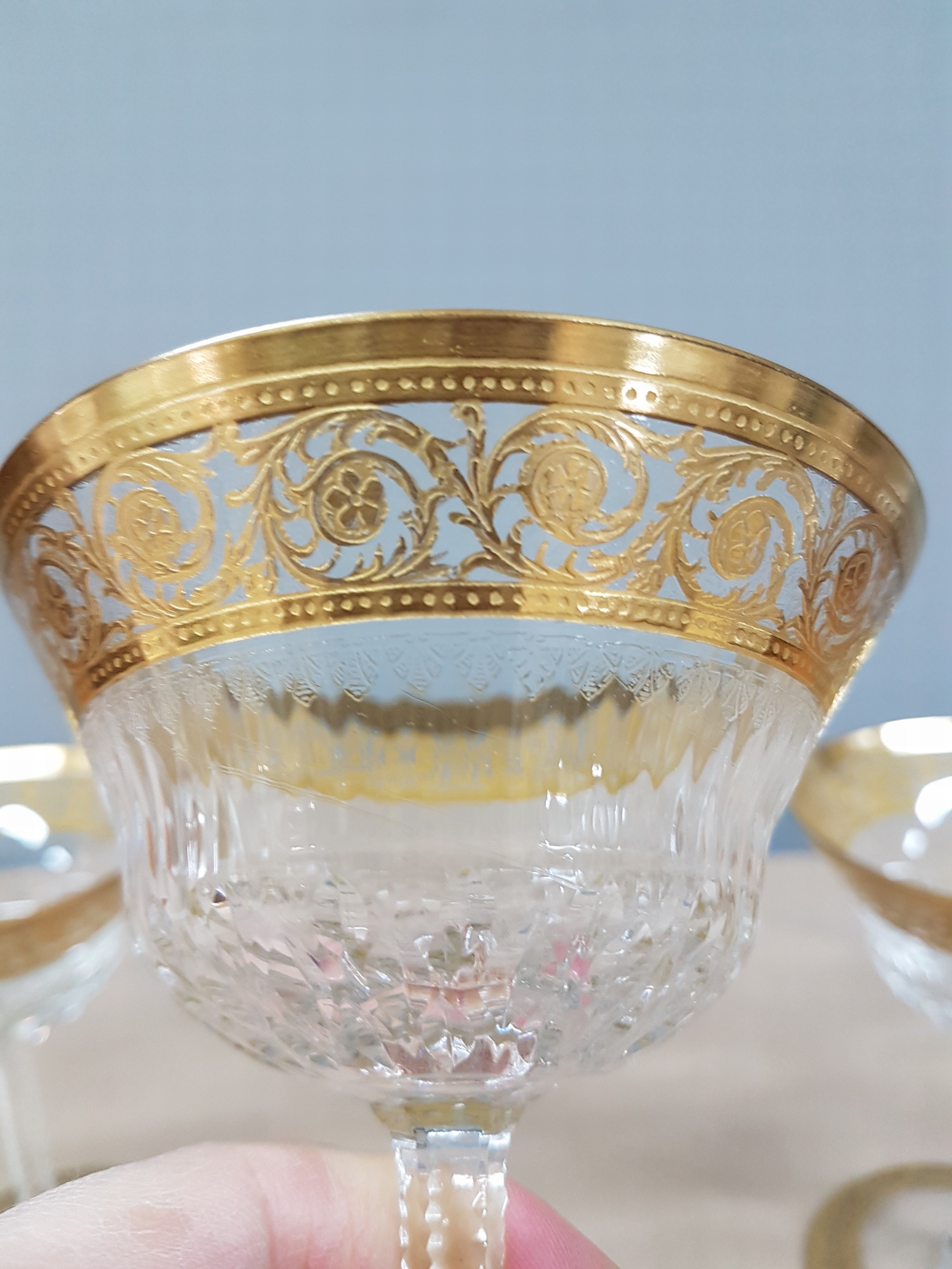 Detail m: 7 Champagnerschalen, Saint Louis, Dekor Thistle, farbloses Kristallglas, breit geätzte Goldbordüre, H. 13 cm