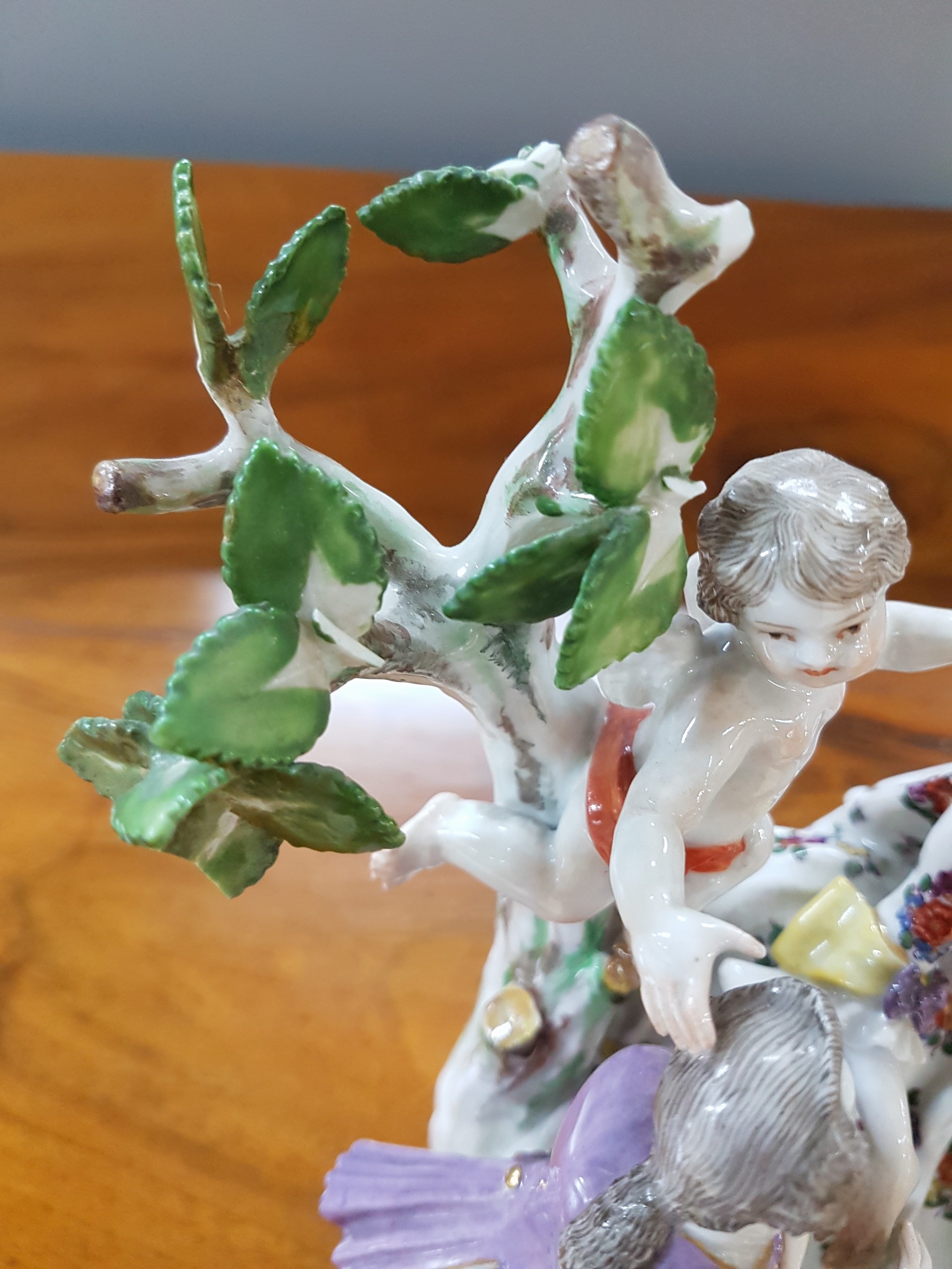 Detail h: Porzellanfigurengruppe, Meissen, um 1900, galante Szenerie mit zwei Putten, bunt bemalt, Blattwerk des Baumes bestoßen und teils fehlend, H. ca. 18cm