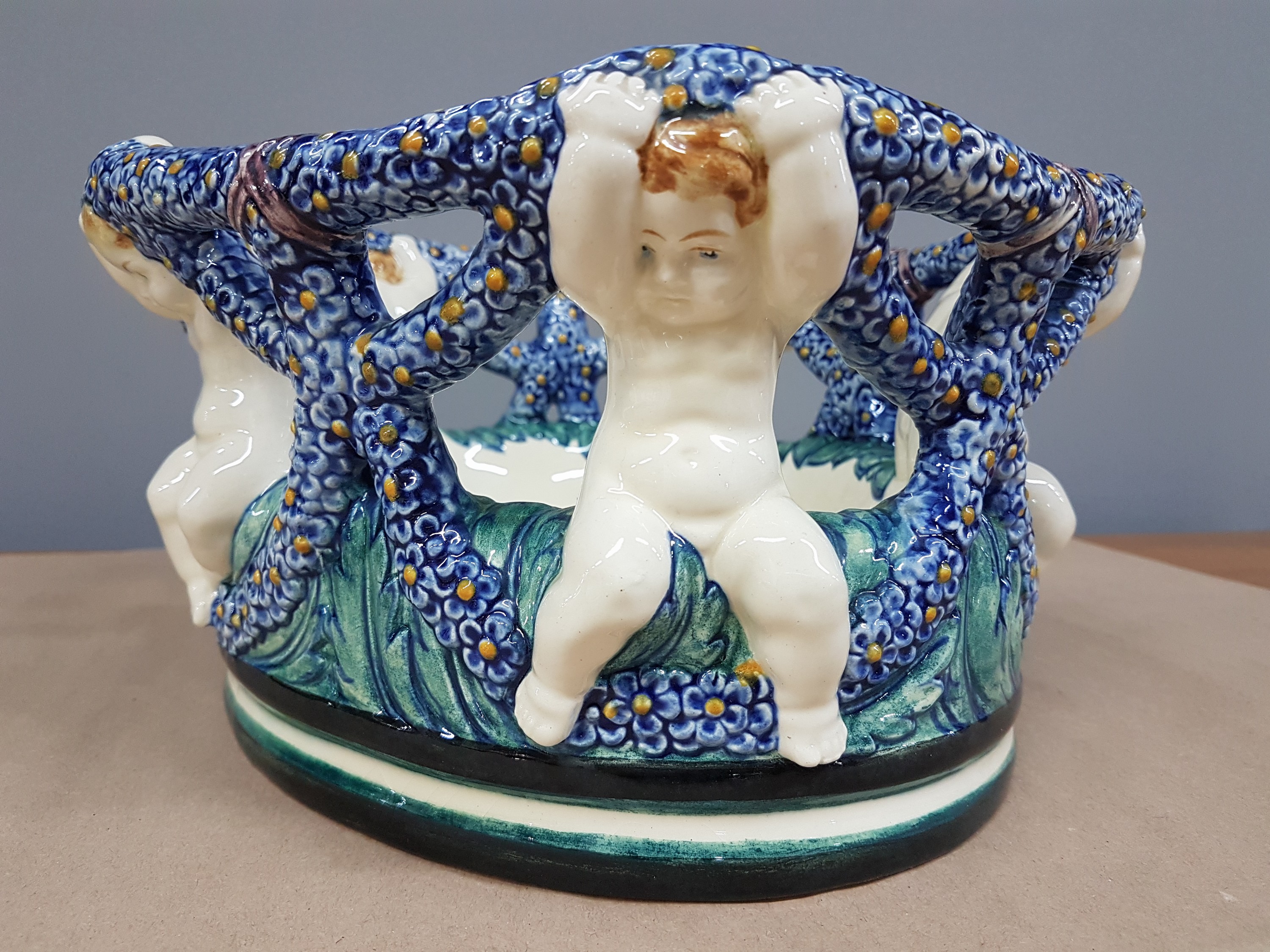 Detail a: Fruchtschale, Karlsruher Majolika, Entwurf Wilhelm Süs, 5 Amoretten mit Vergißmeinnichtranke, bunt bemalt, Modellnr. 1224, am Boden gemarkt, H.ca. ...