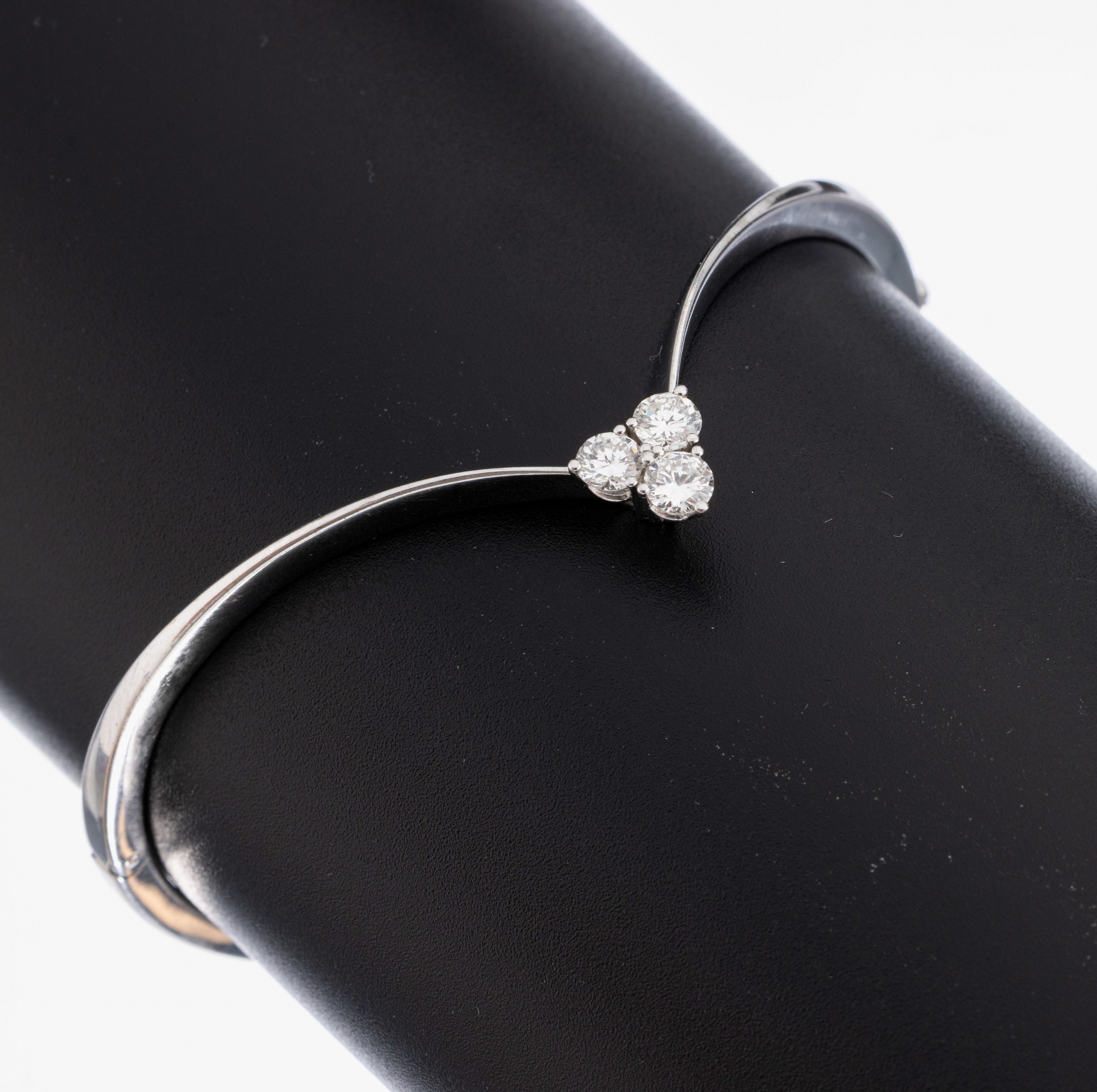 18 kt Gold Brillant-Armreif, WG 750/000, geschwungene Grundform, 3 im Dreieck angeordnete Brillanten zus. ca. 0.60 ct feinesWeiß-Weiß/vs, D. ca. ...